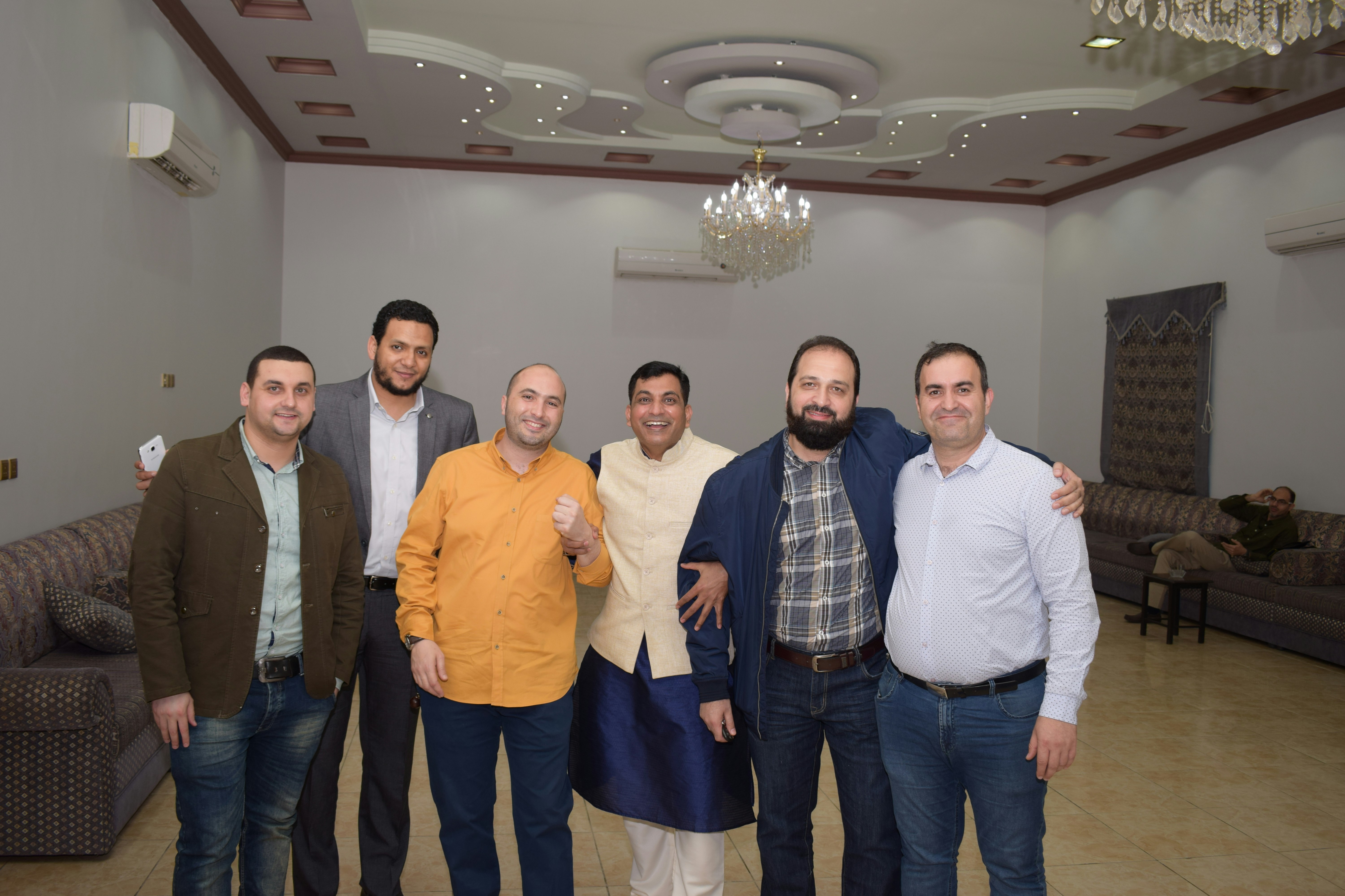 Group of men at a social event, confident poses, dark venue, warm lighting