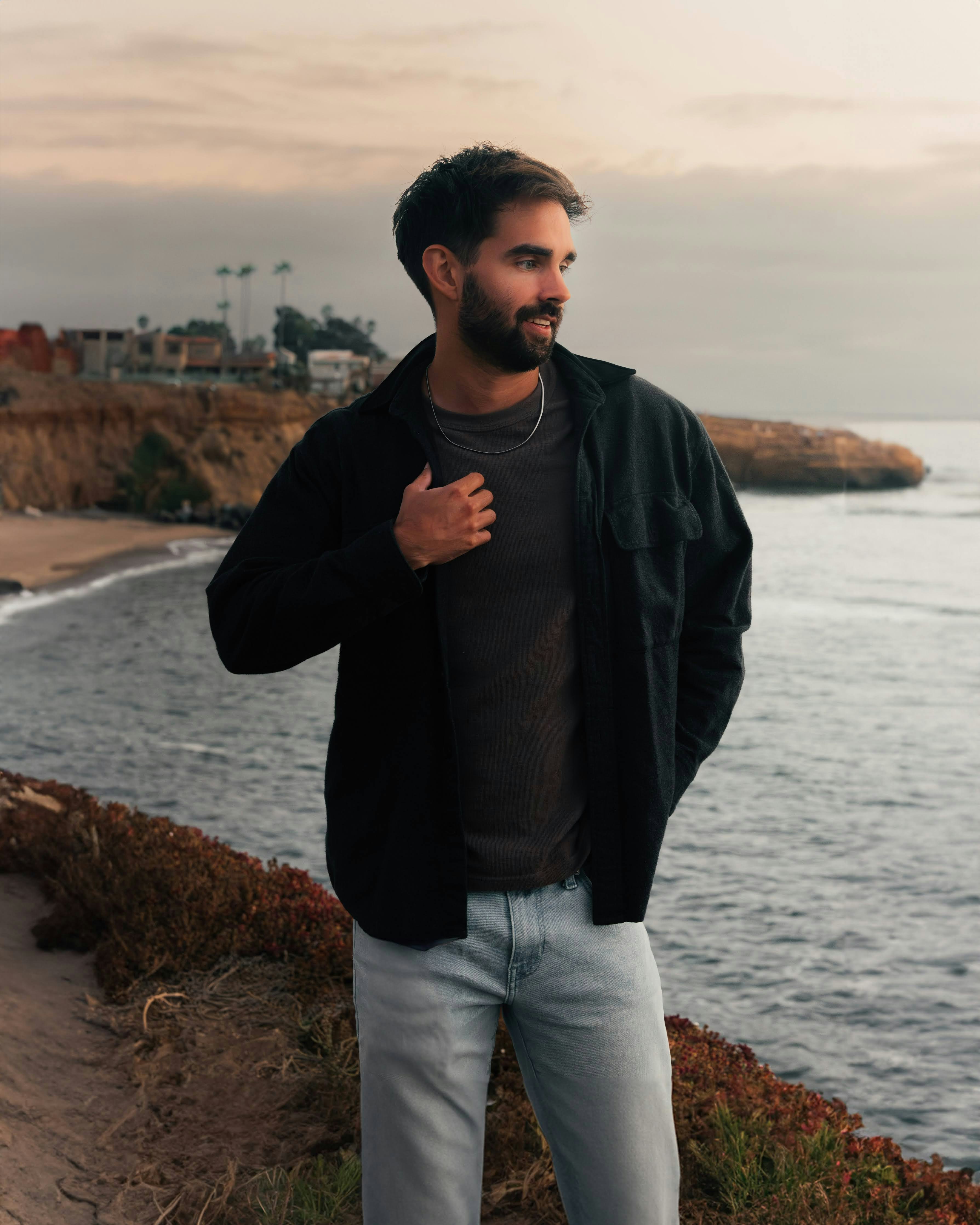 A man standing on a cliff next to the ocean