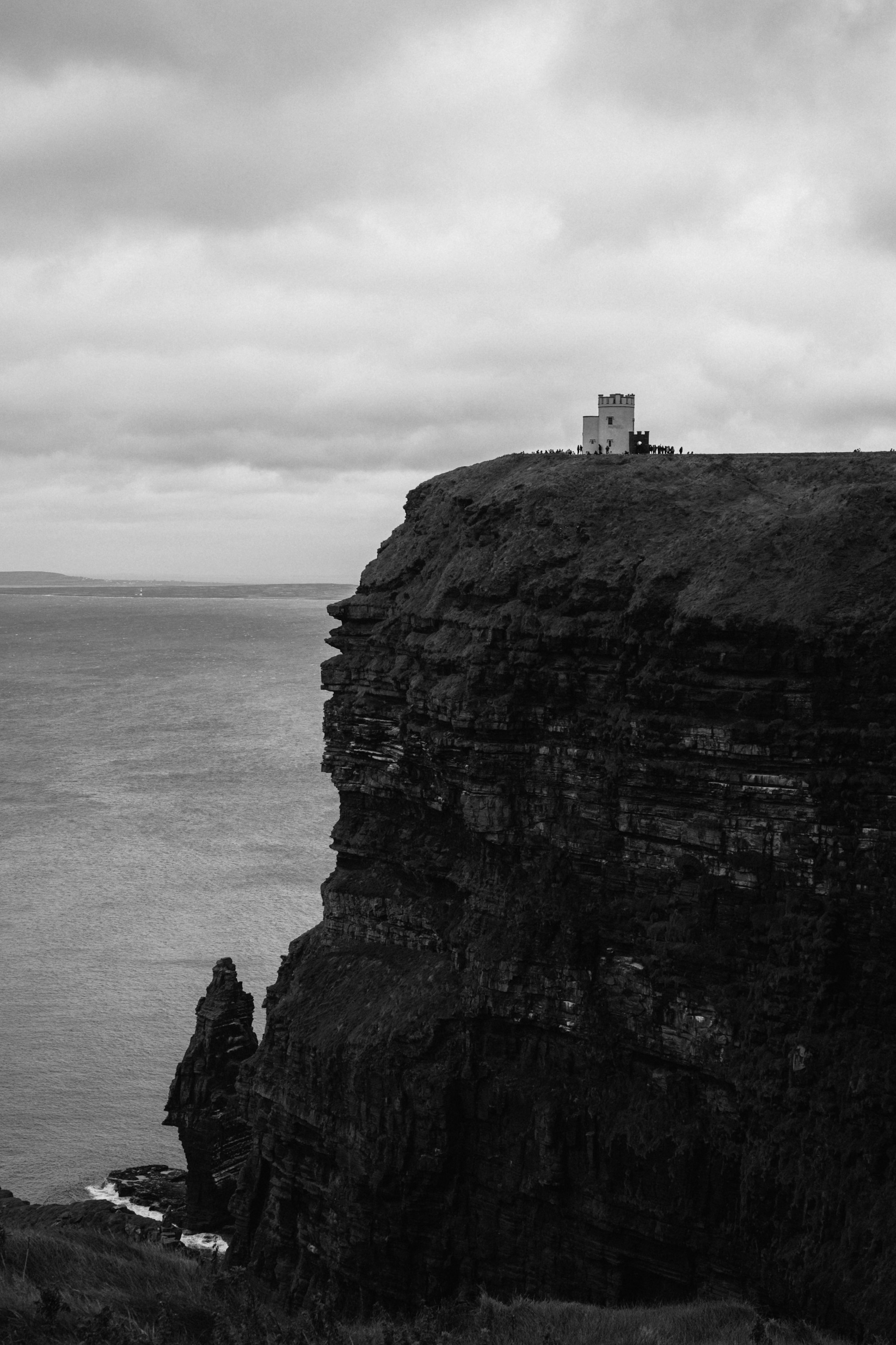 Uma foto preto e branco de um farol em um penhasco