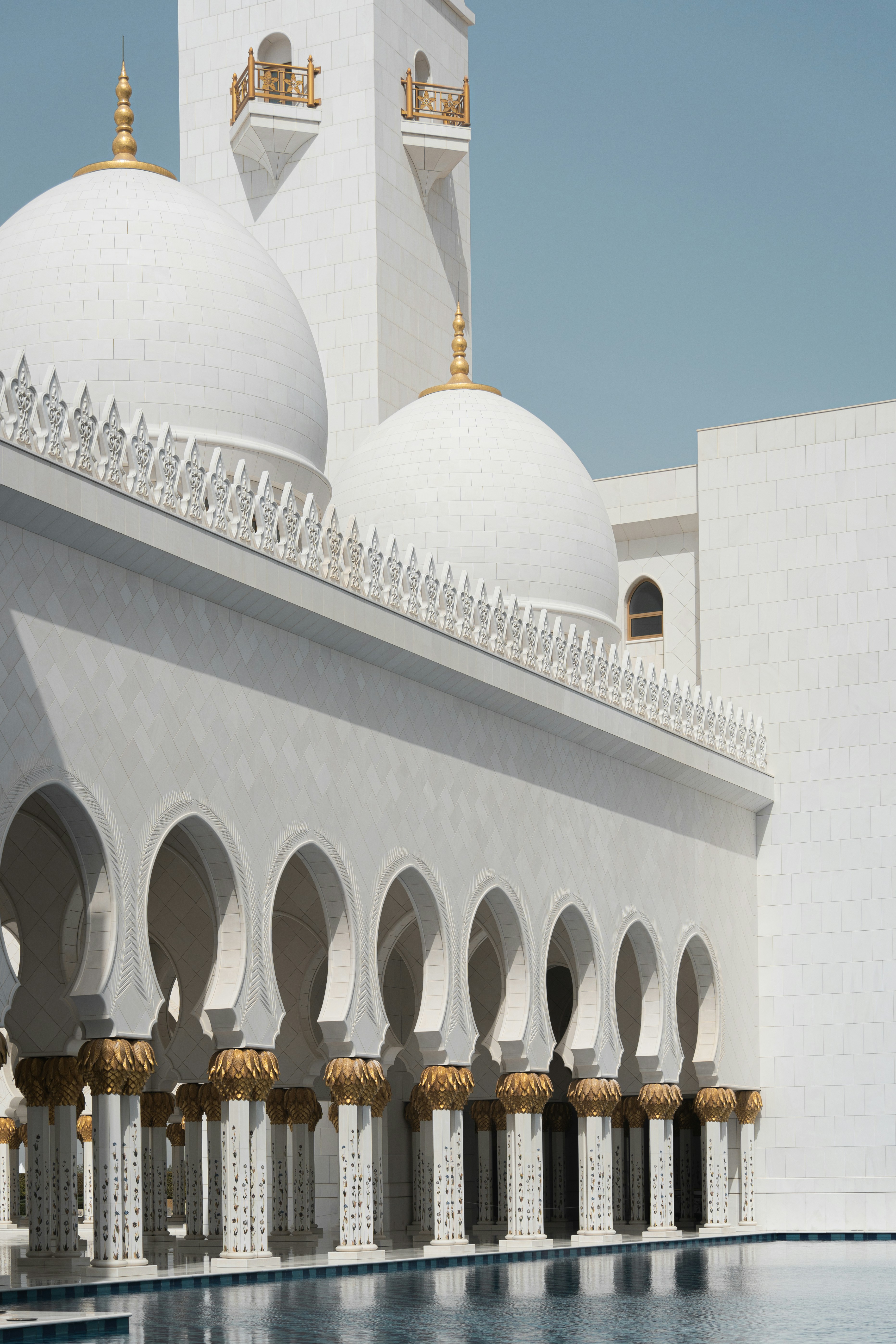 A large white building with a pool in front of it