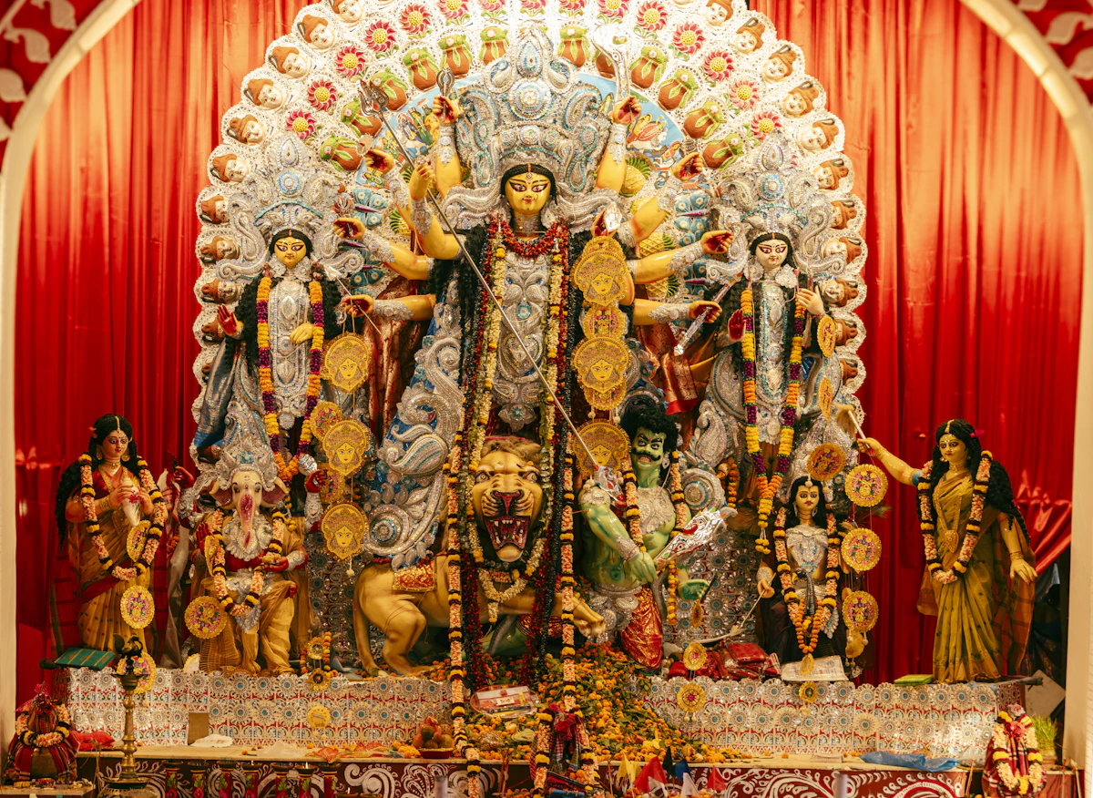 An ornate Durga Puja display decorated with flowers and warm lights