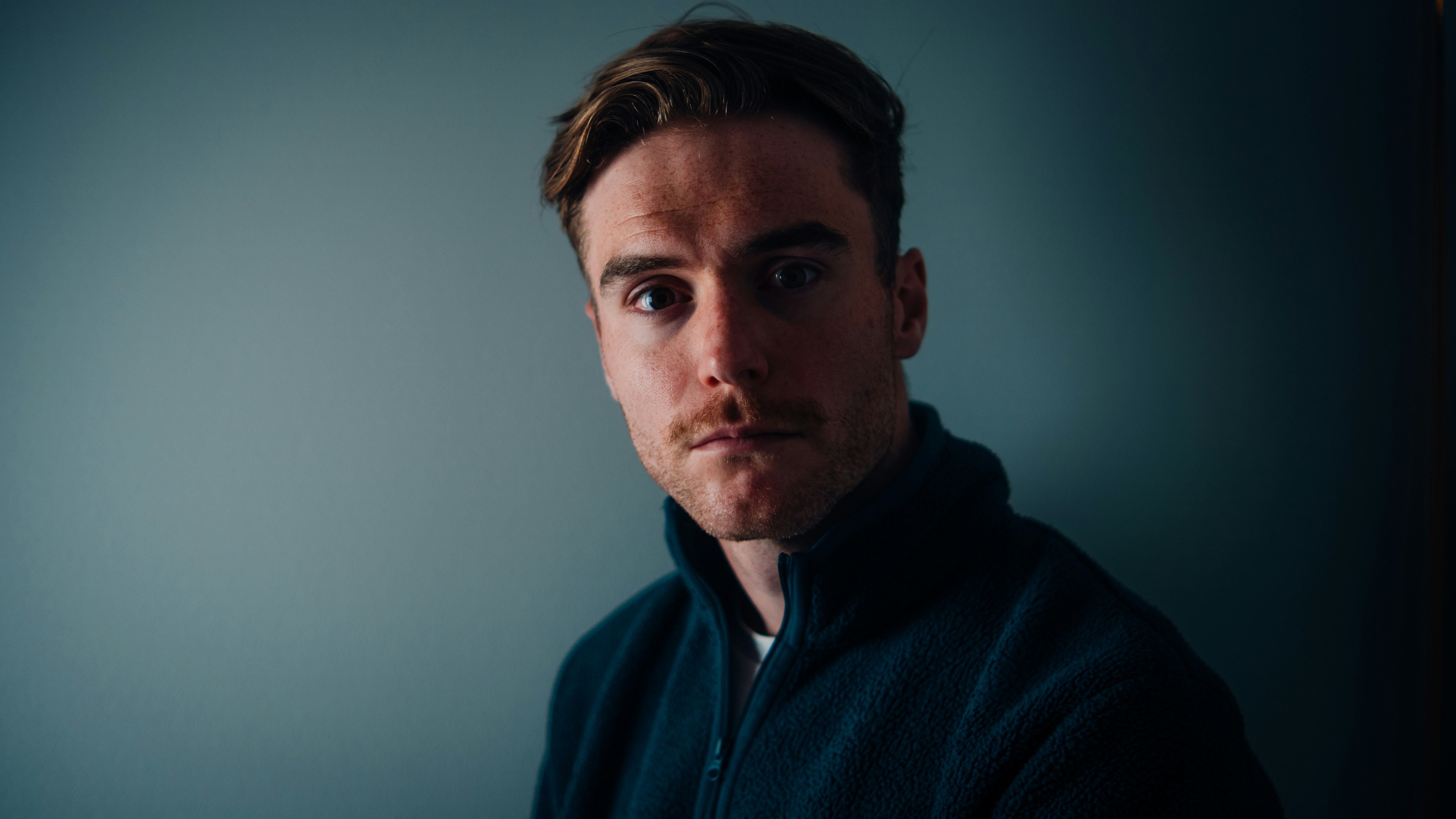 Ein Mann in einer schwarzen Jacke, der in die Kamera schaut