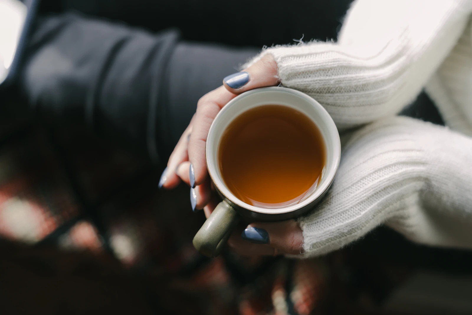 A woman holding a warm cup of tea in both hands