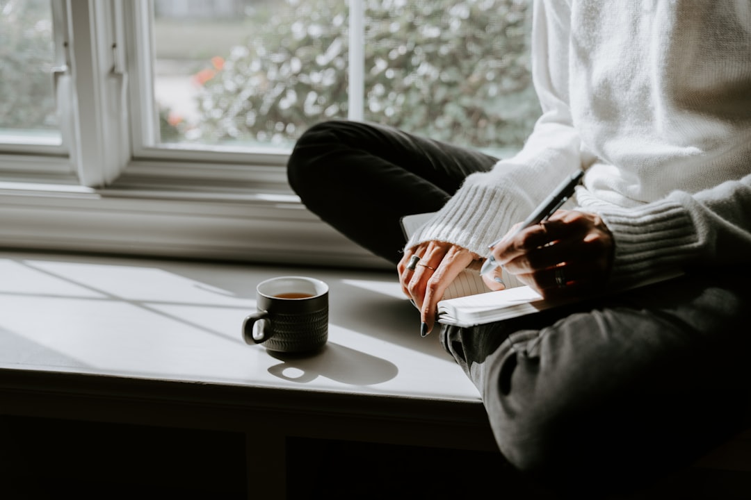 person reflecting alone with journal and tea at home