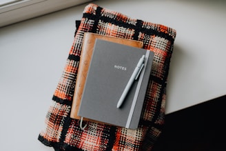 A notepad and pen sitting on top of a blanket
