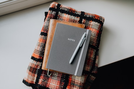 A notepad and pen sitting on top of a blanket