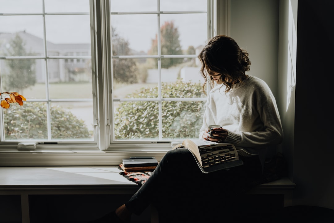 Mujer leyendo un libro en el alféizar de una ventana, evocando la introspección de Veronika decide morir de Paulo Coelho