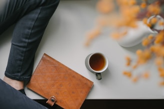 A person sitting at a table with a laptop and a cup of coffee