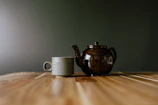 A teapot and a cup on a wooden table