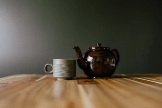 A teapot and a cup on a wooden table