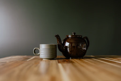 A teapot and a cup on a wooden table