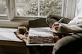 A person sitting in a chair writing on a piece of paper