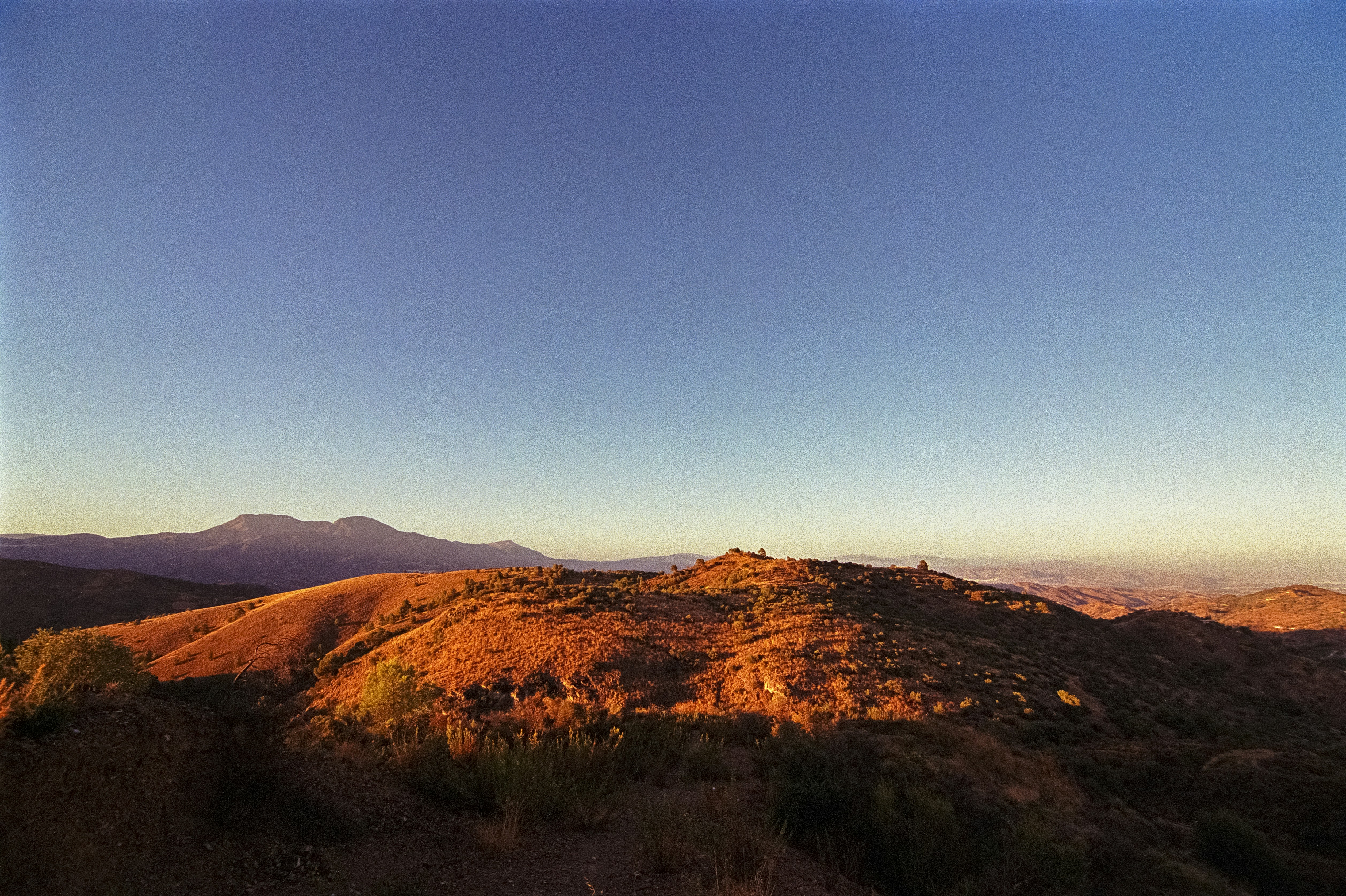 A view of a mountain with a blue sky in the background, 