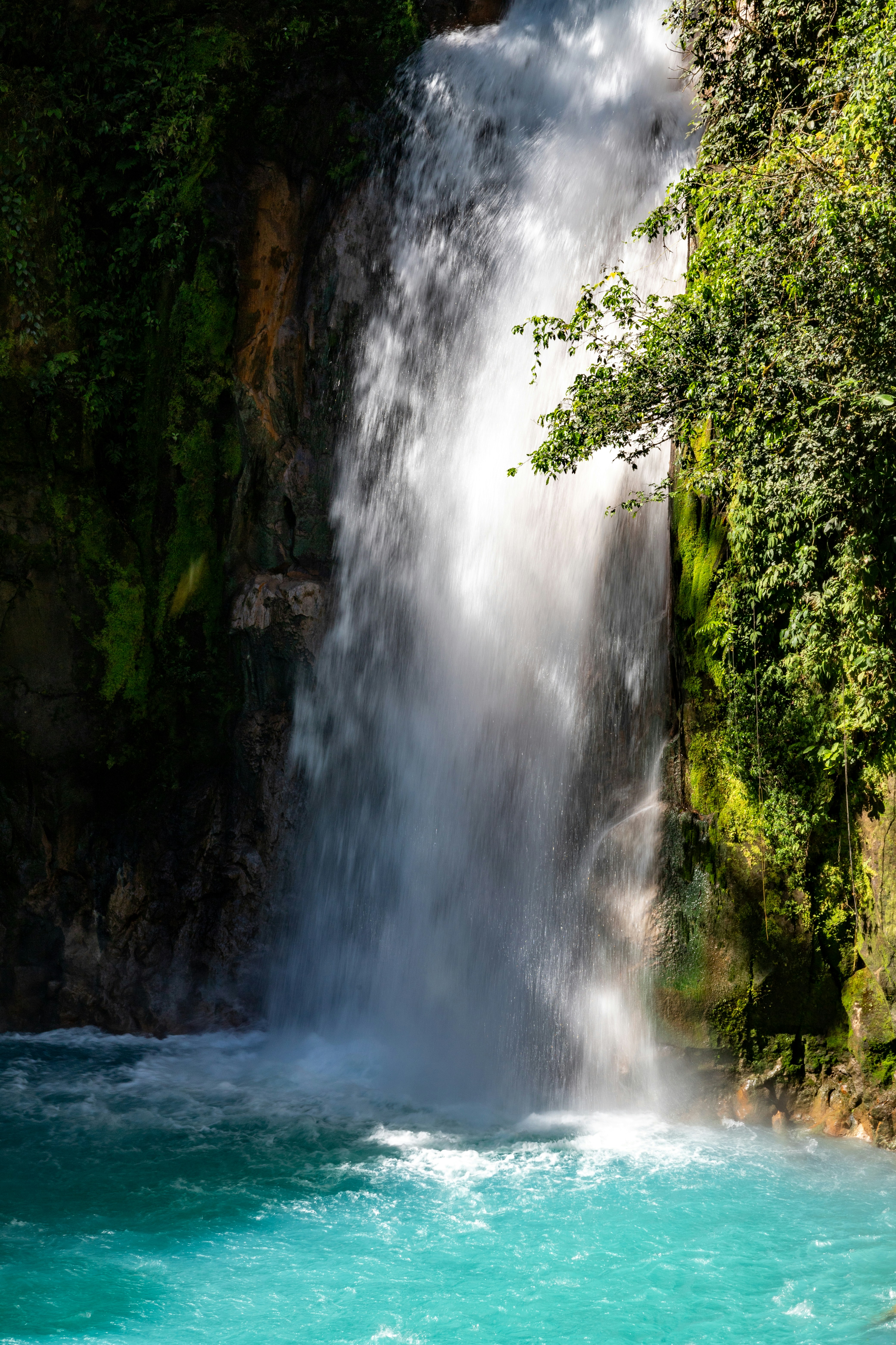 A large waterfall with a blue pool in front of it