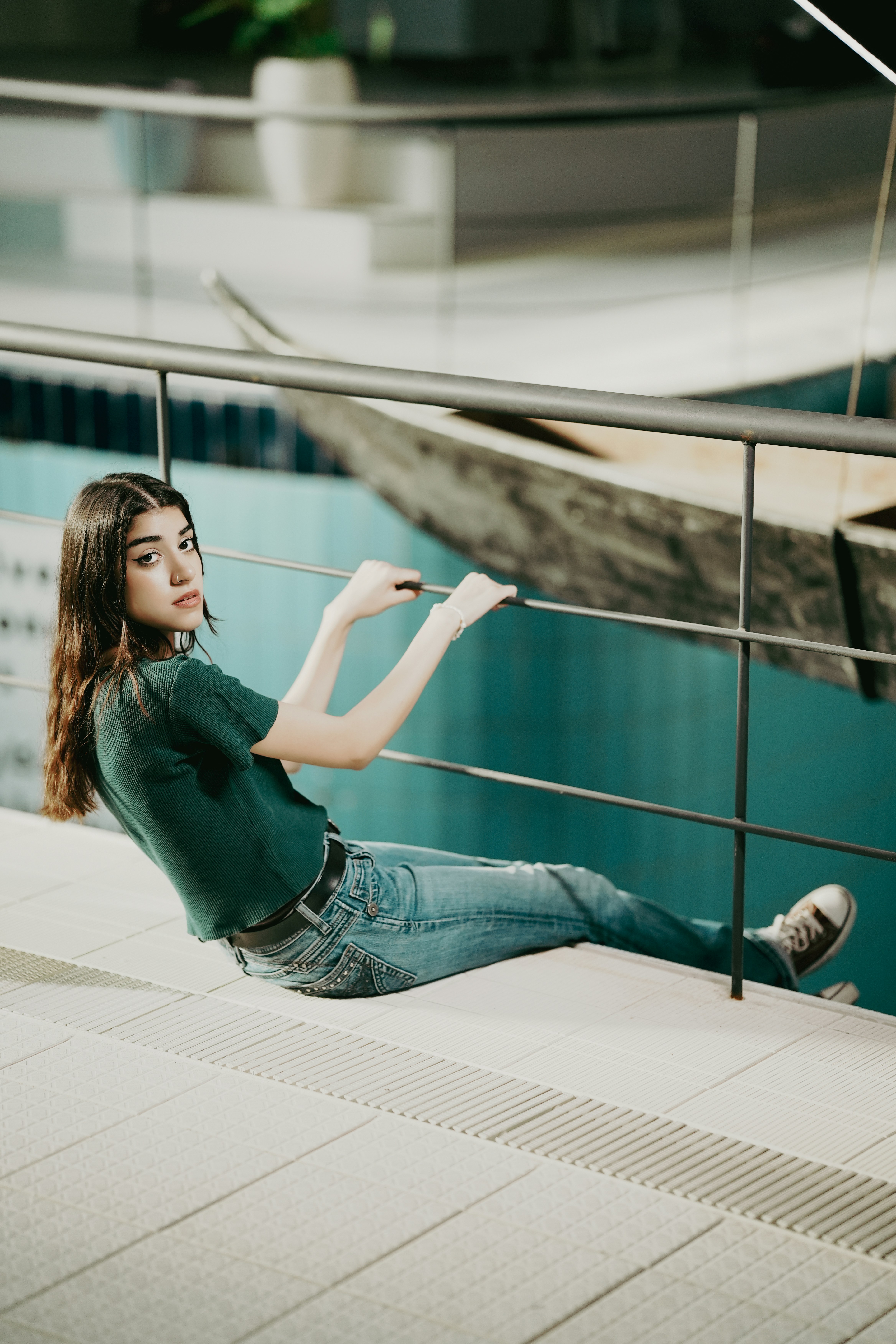A woman is sitting on a railing near a body of water photo – Free Girl ...