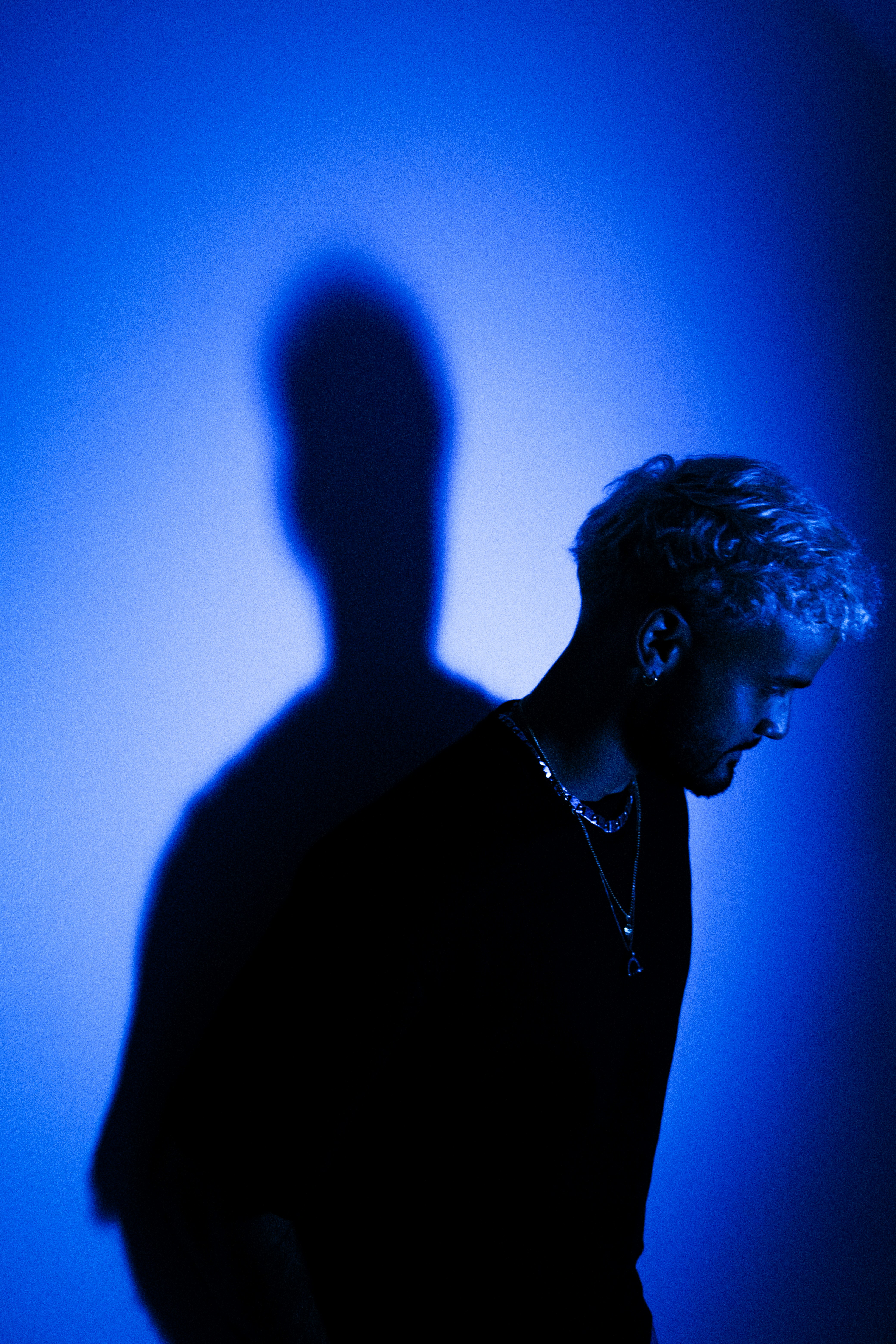 A man standing in front of a blue wall