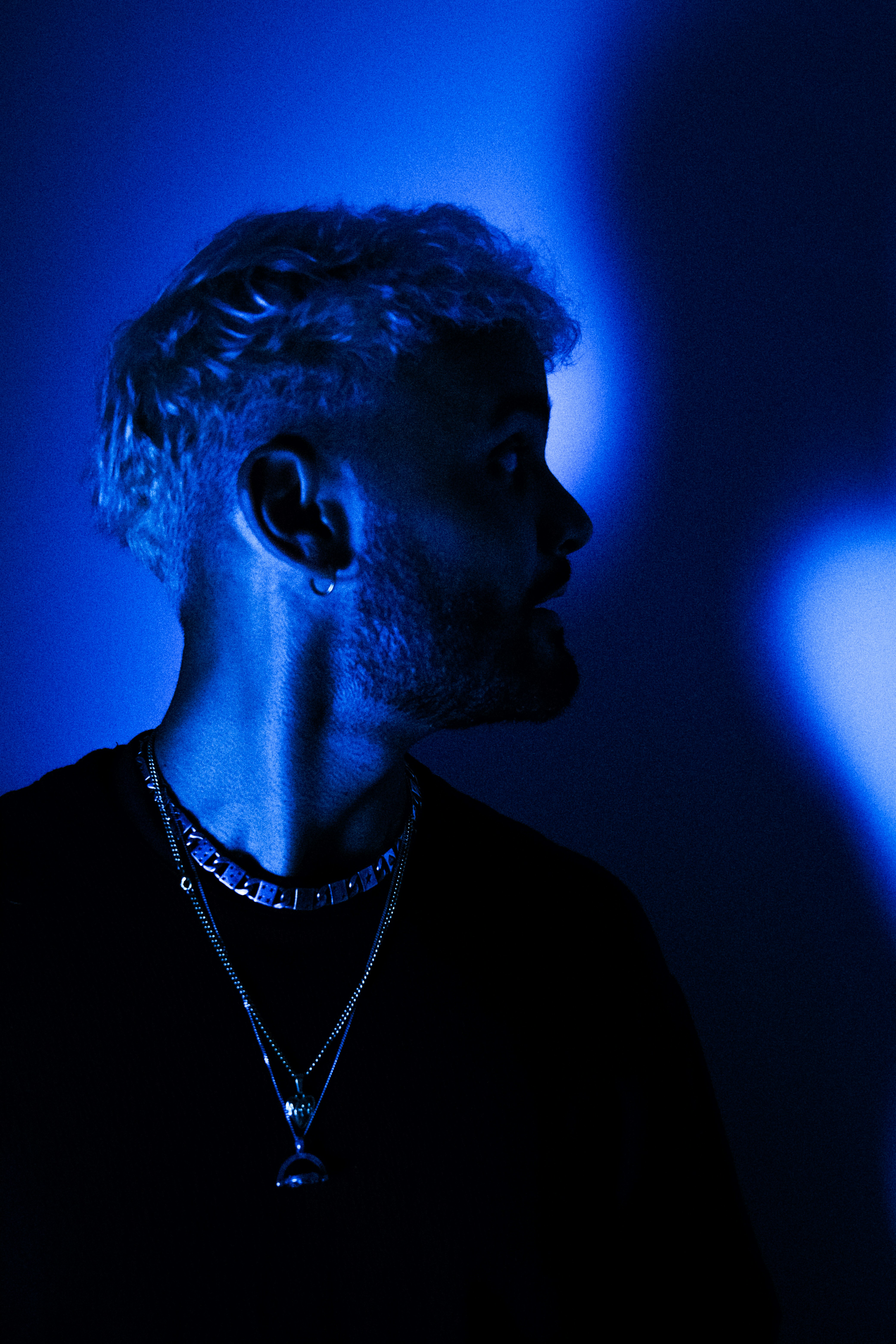 A man standing in a dark room with a blue light behind him