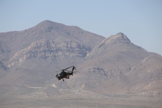 A military helicopter flying over a mountain range