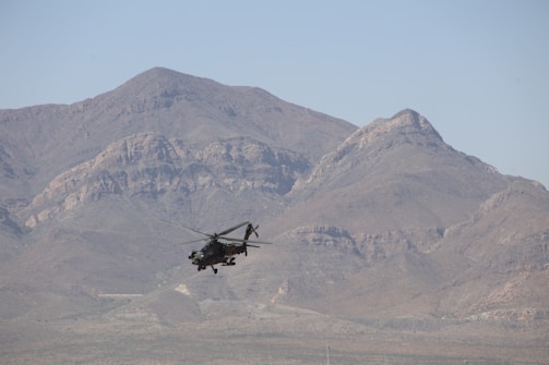 A military helicopter flying over a mountain range