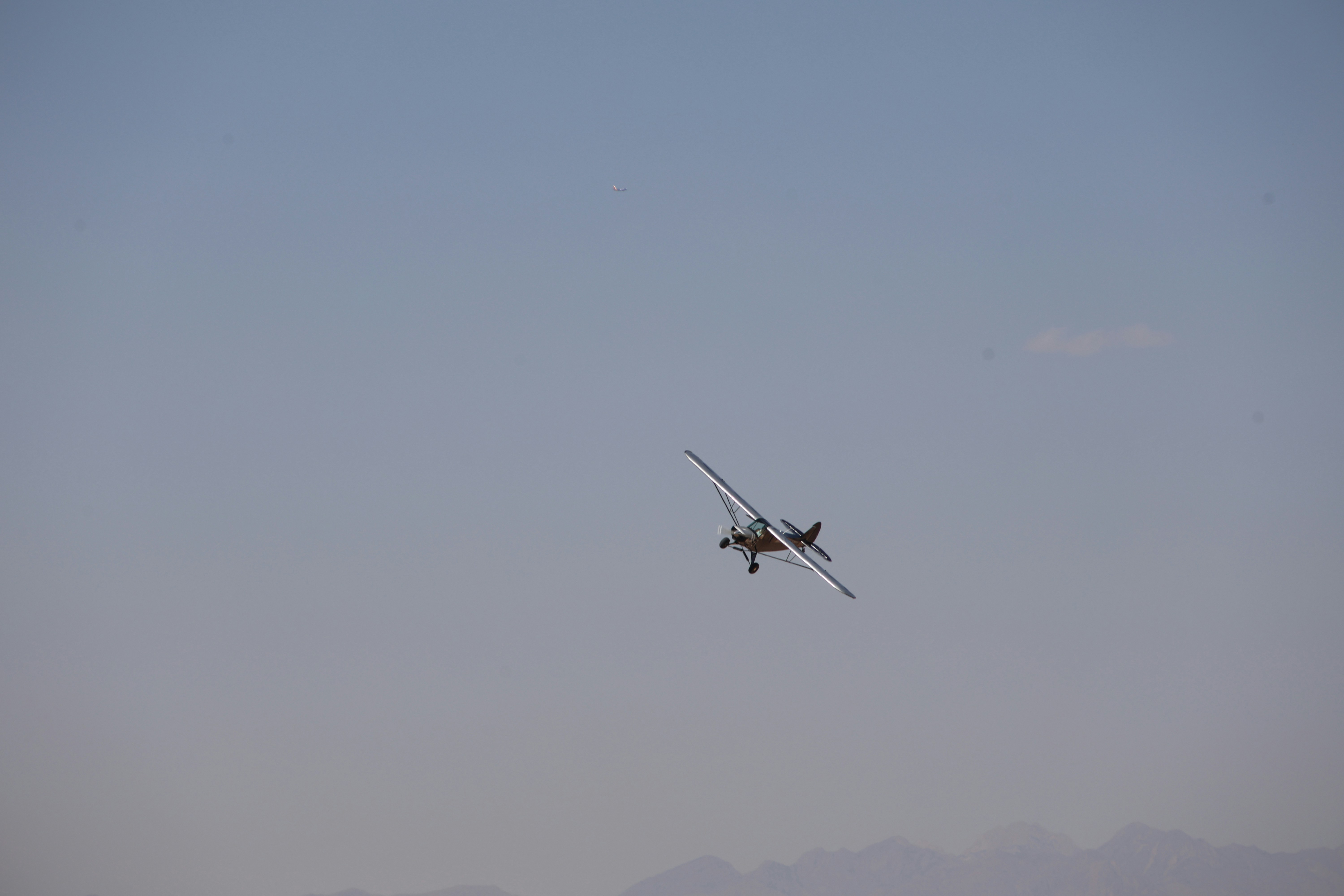 A plane flying in the sky with mountains in the background, 