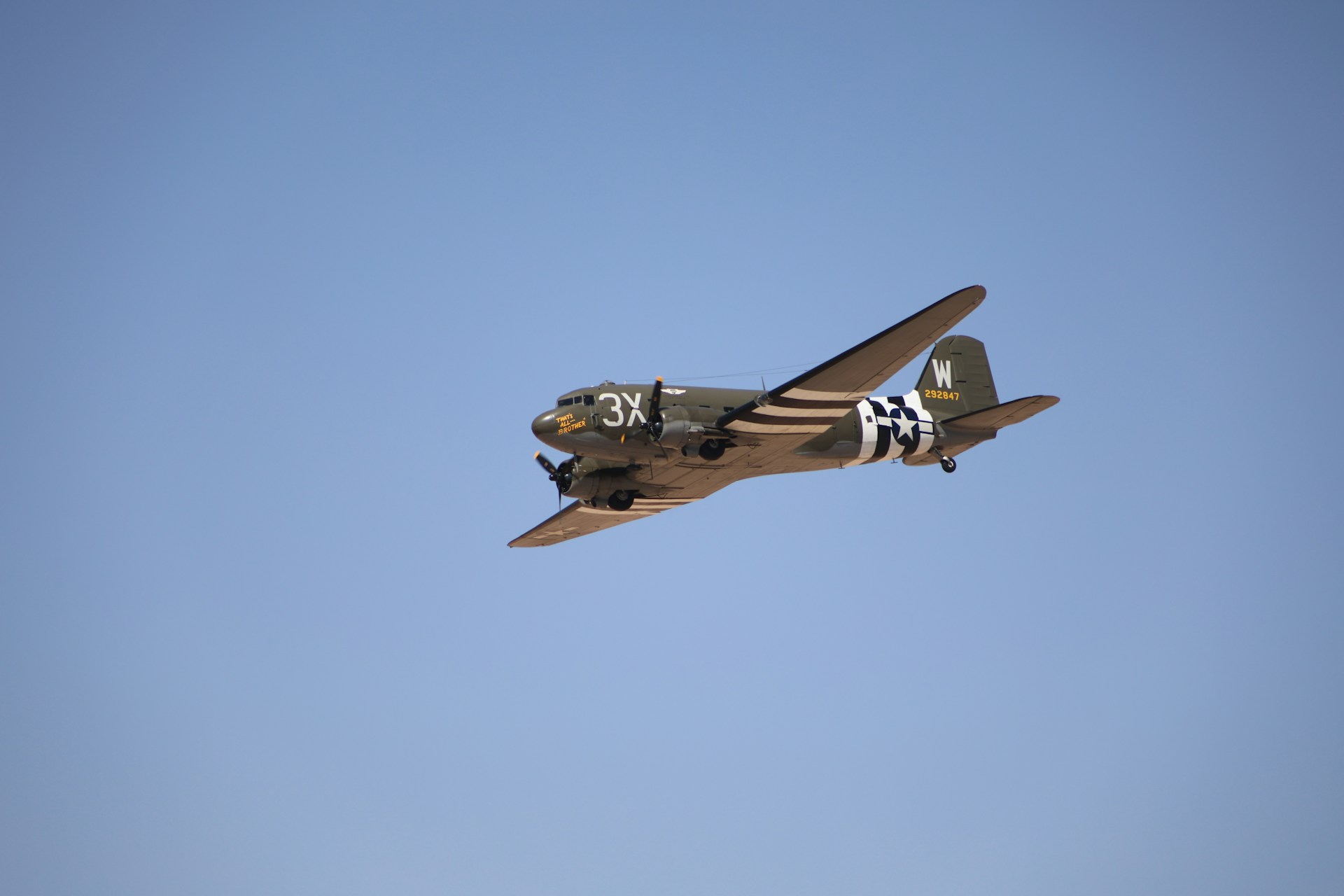 A small airplane flying through a blue sky