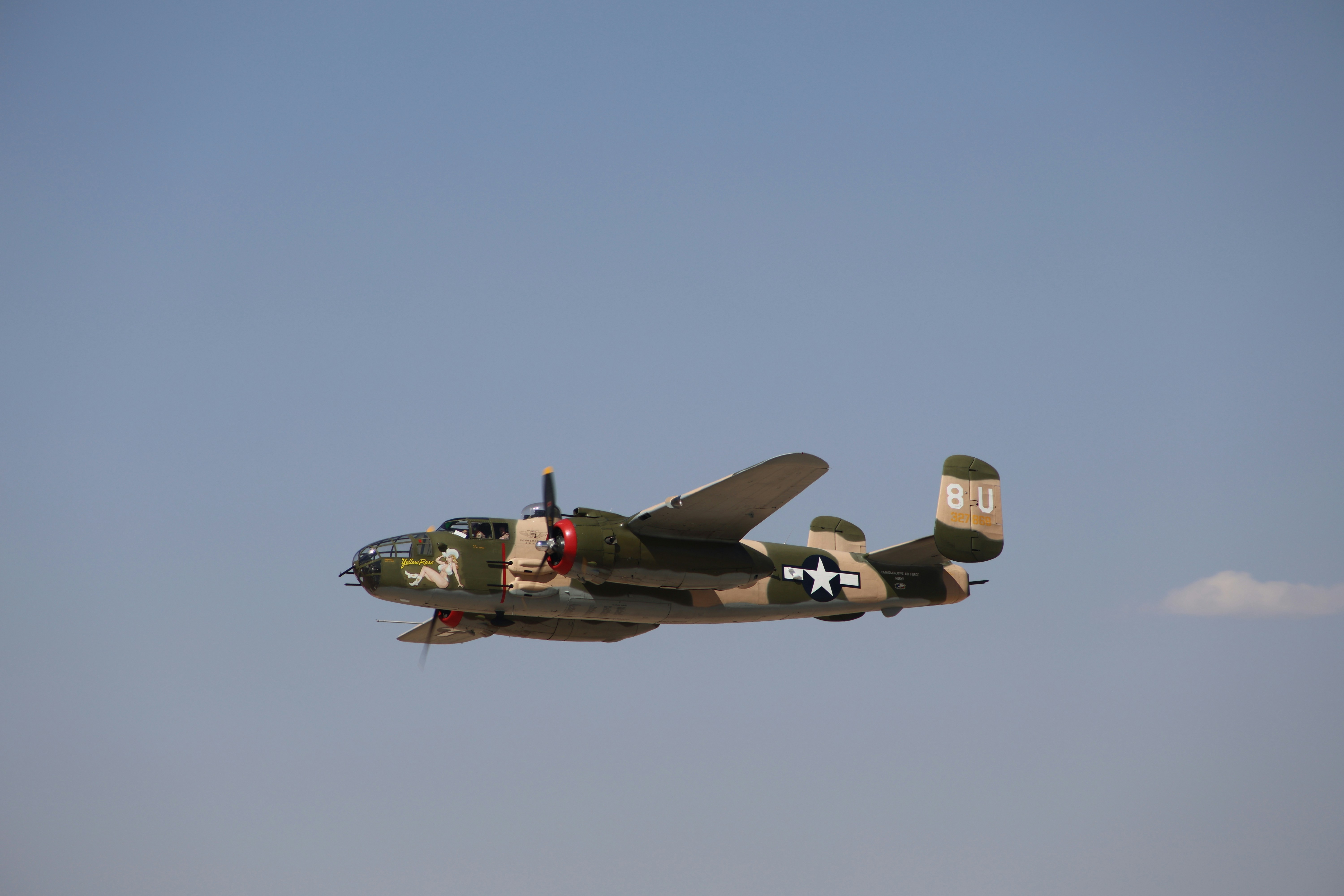 A military plane flying through a blue sky, 