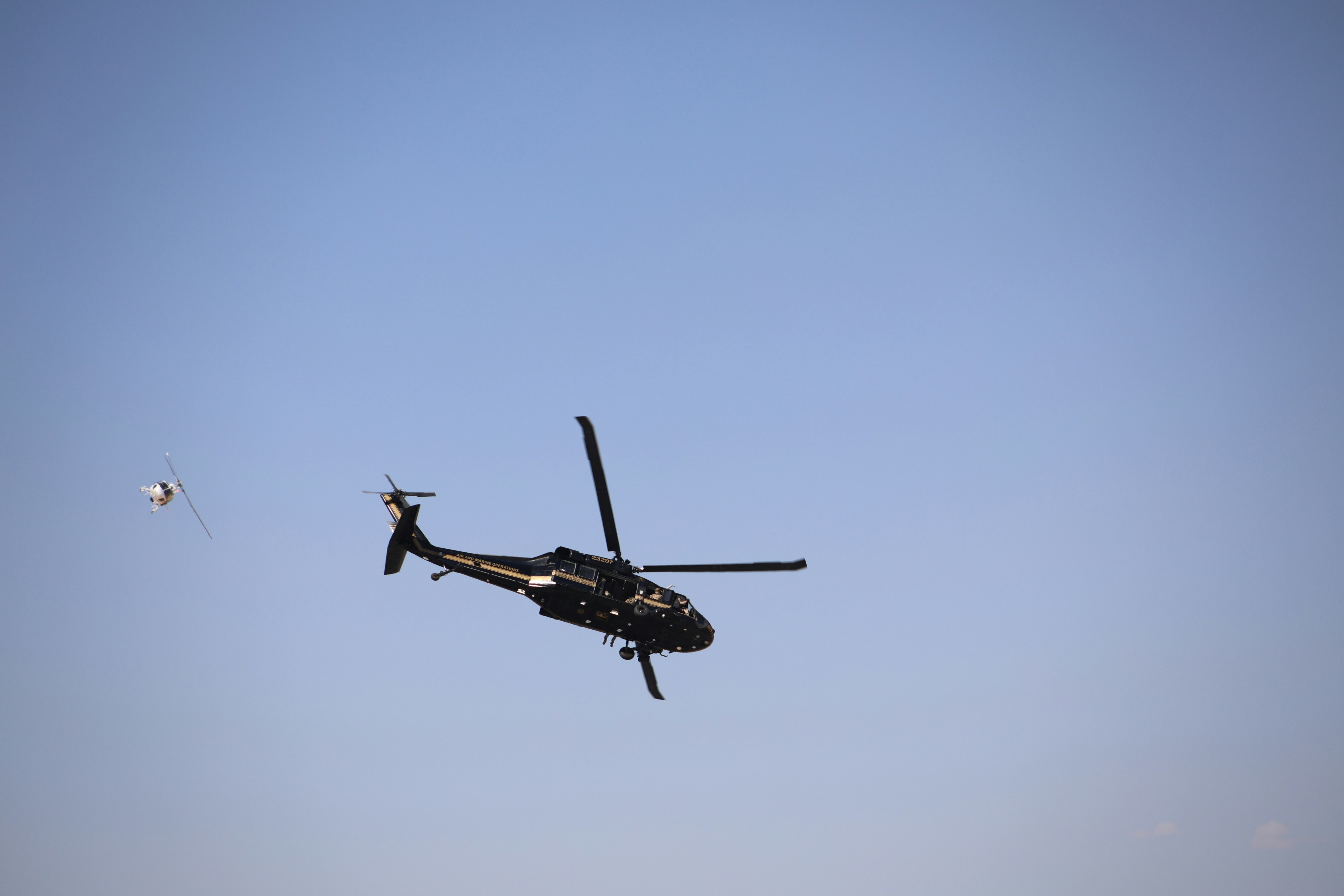 Ein Hubschrauber, der mit einem Drachen im Vordergrund durch den blauen Himmel fliegt