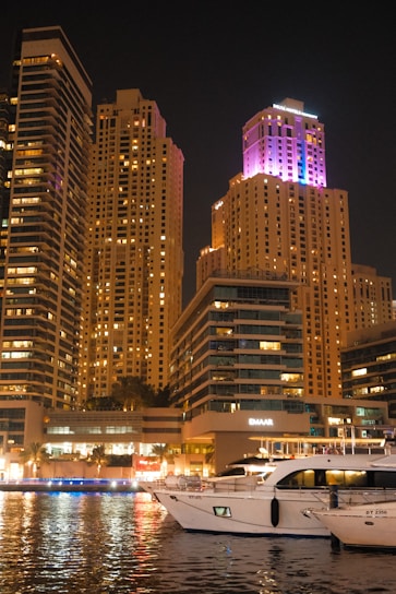 A boat in the water in front of a city at night