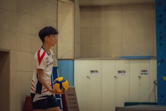 A boy holding a soccer ball in a gym