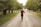 A woman walking down a dirt road holding a wine glass