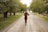 A woman walking down a dirt road holding a wine glass