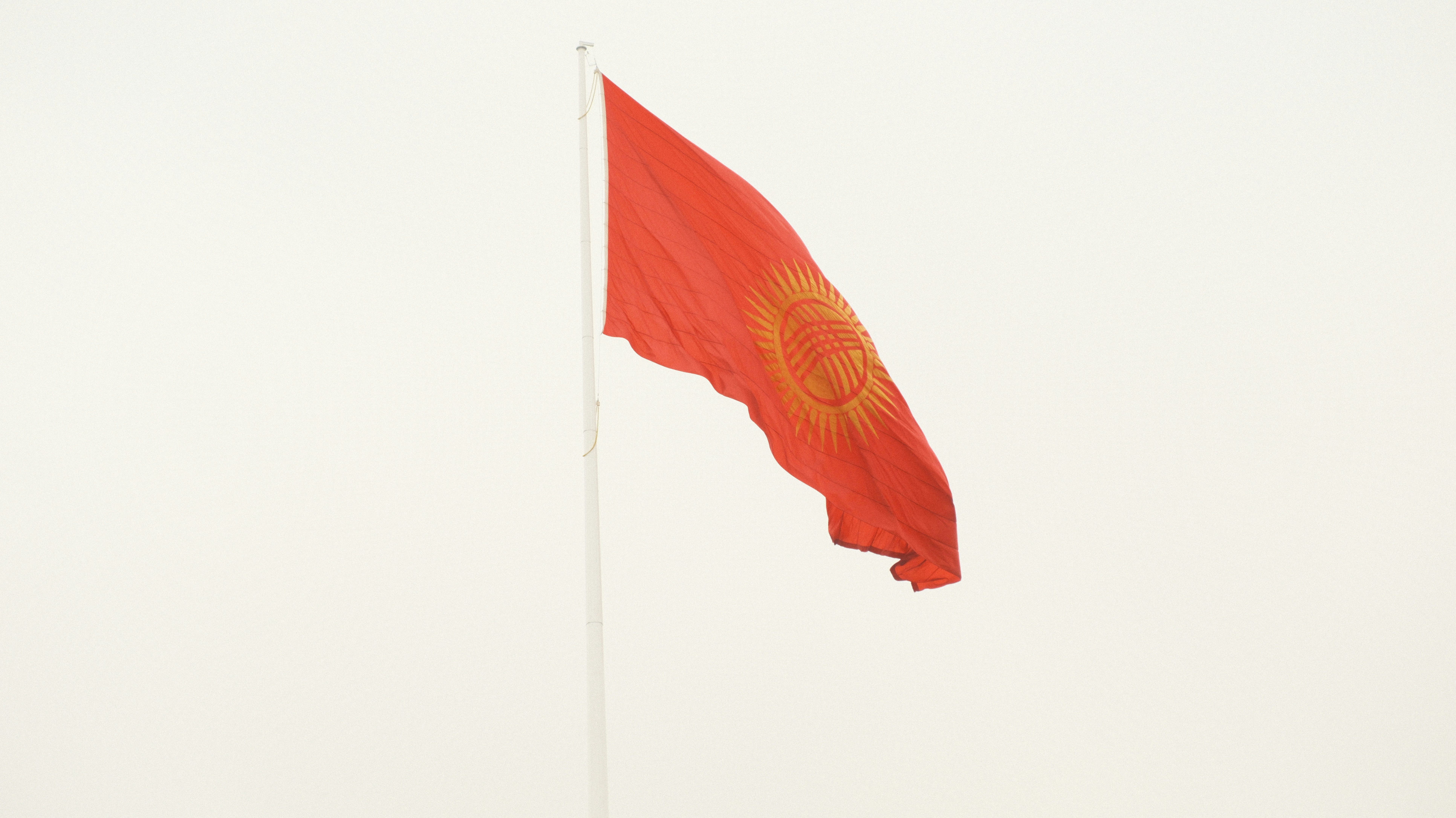A red flag flying in the wind on a pole