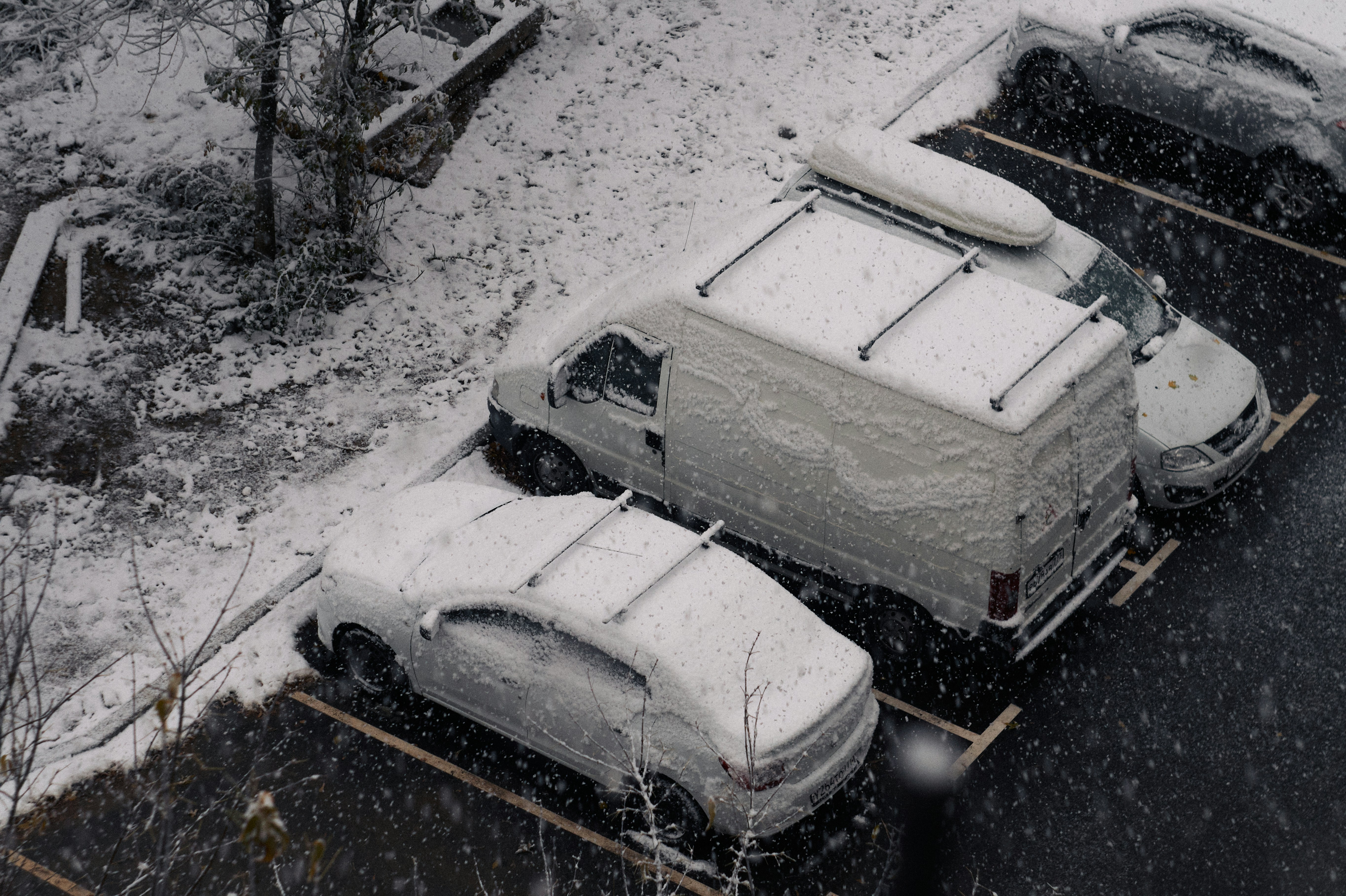 A parking lot covered in snow next to parked cars