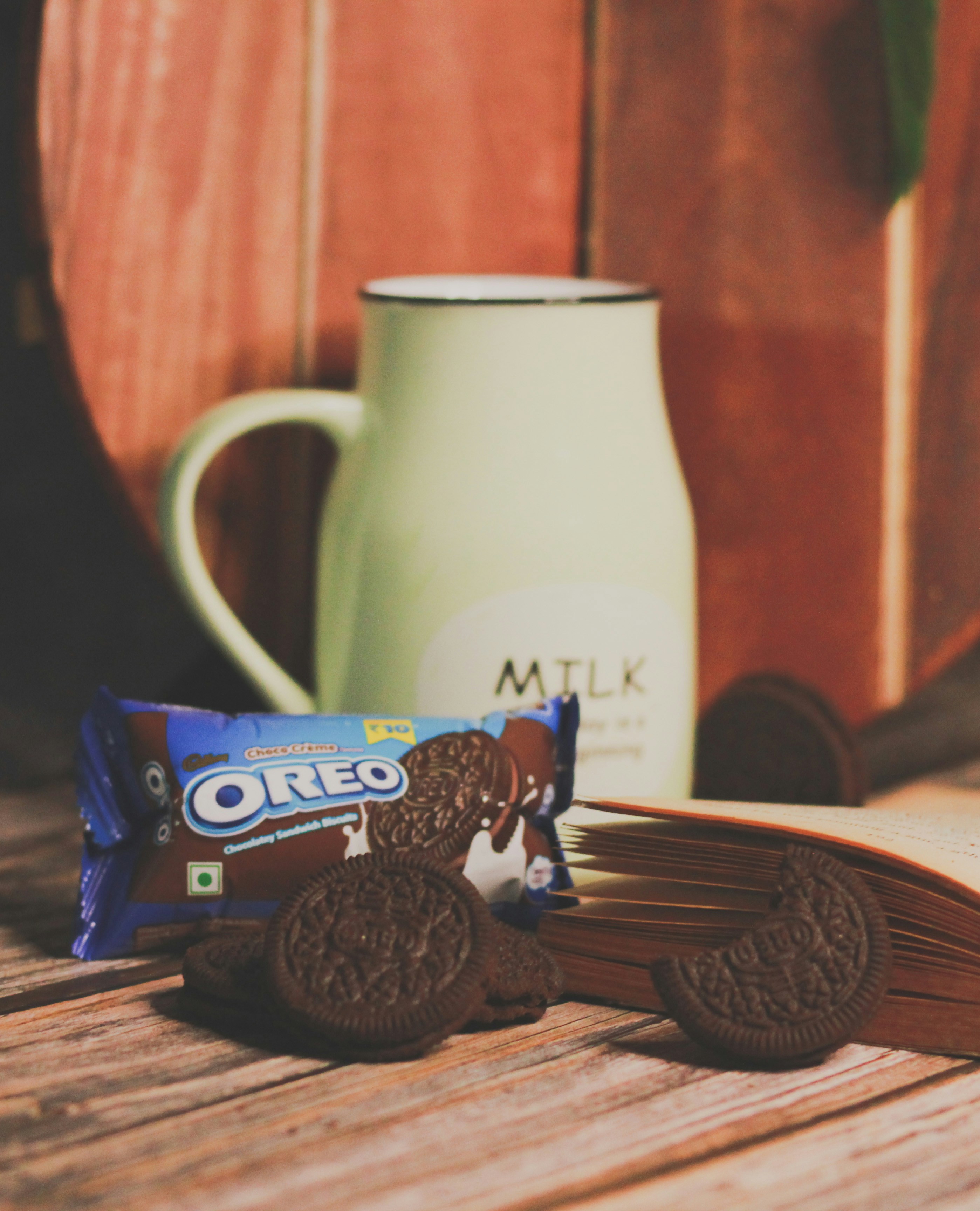 An oreo bar next to a mug of milk and a cookie