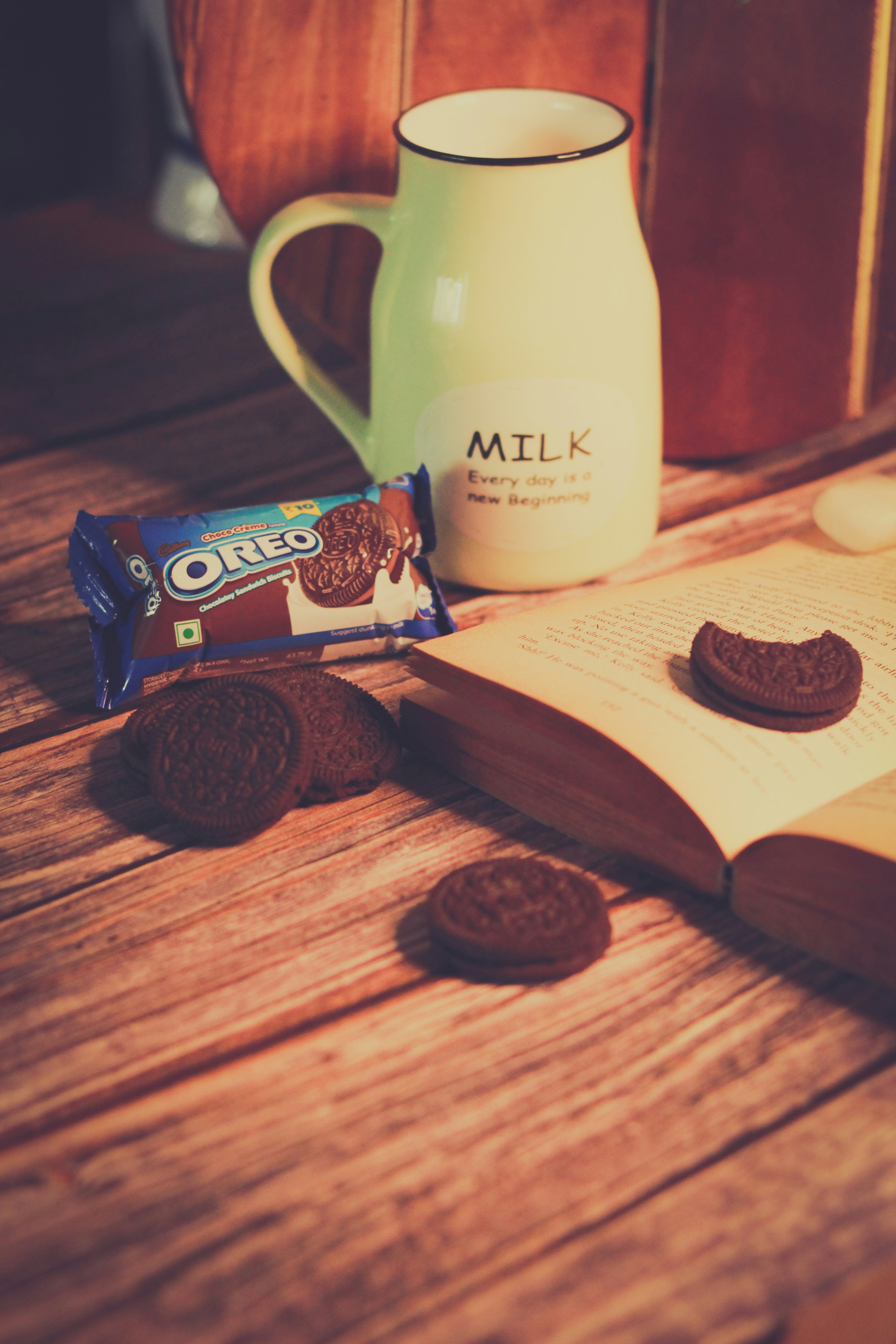 An open book with cookies and milk on a wooden table
