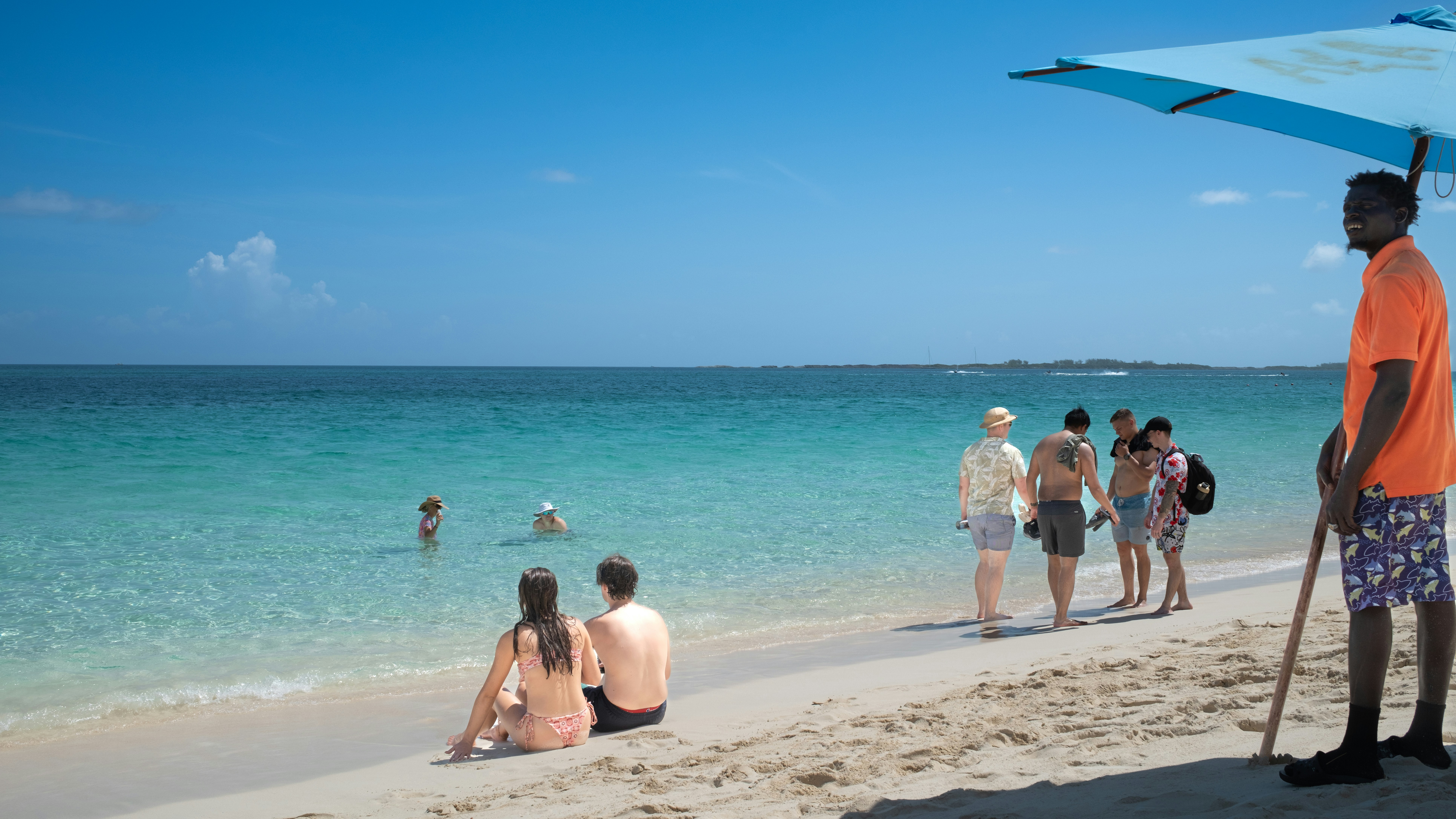 A group of people standing on top of a sandy beach