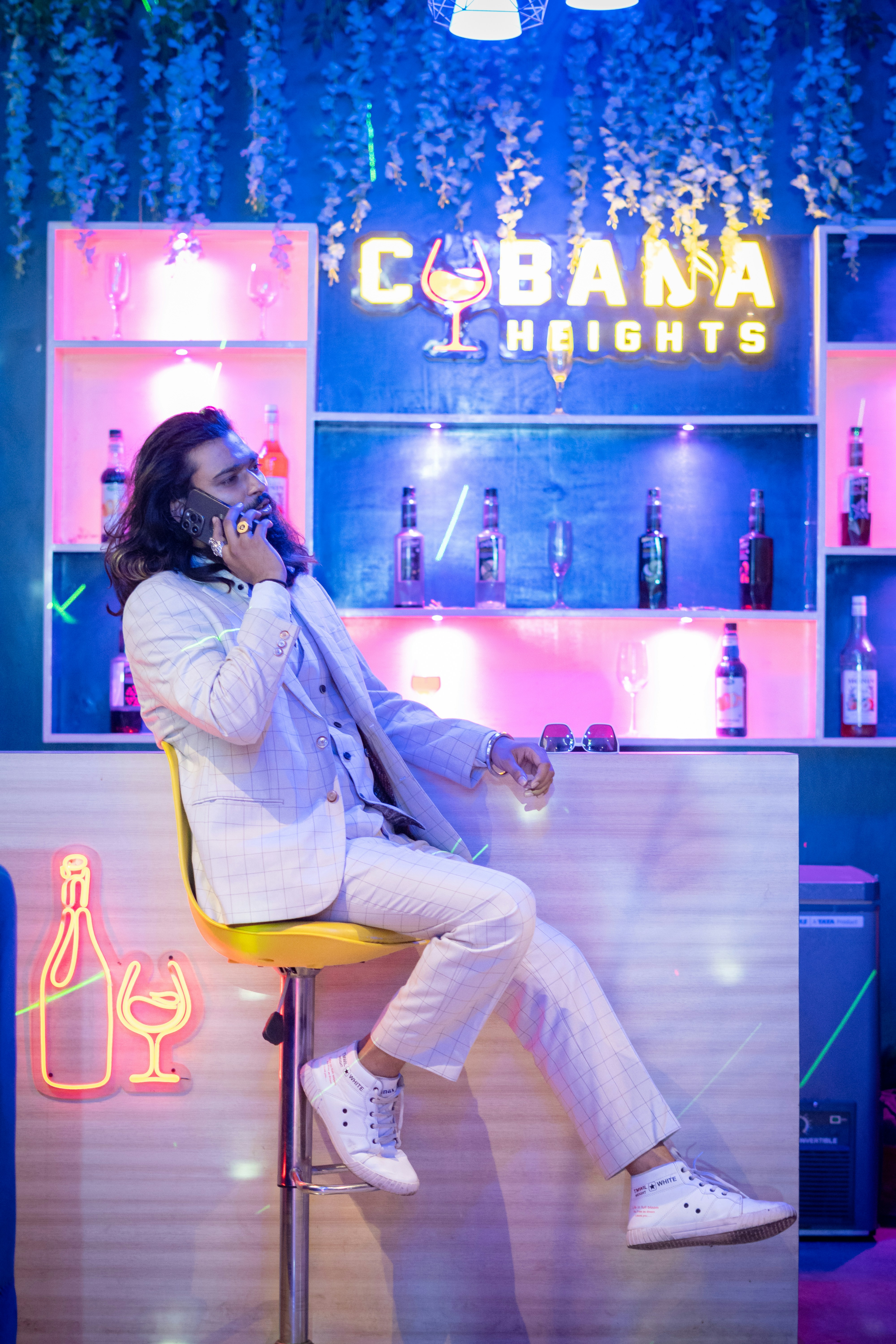 Un homme assis sur un tabouret qui parle au téléphone portable