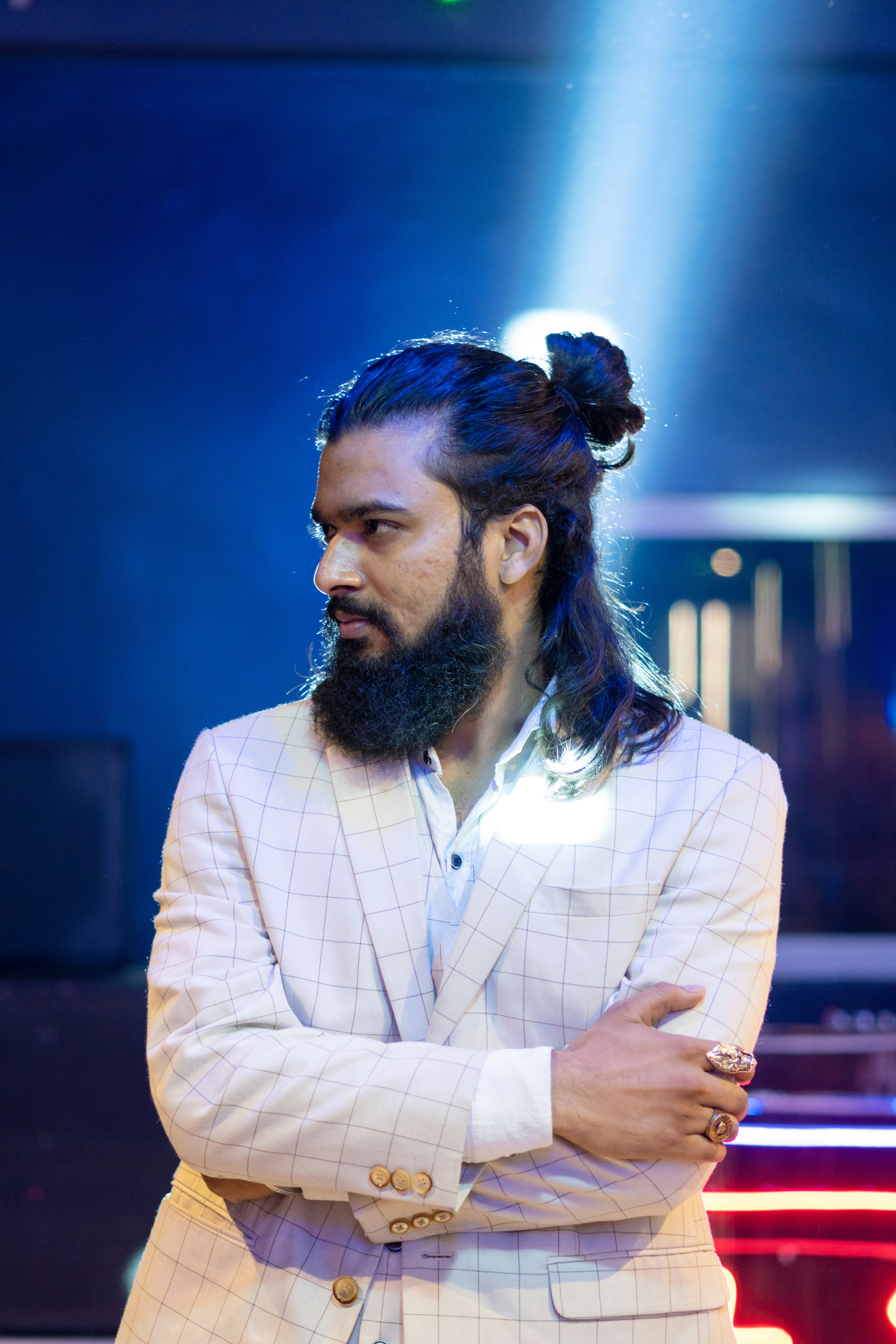 Un homme aux cheveux longs et à la barbe debout devant une voiture