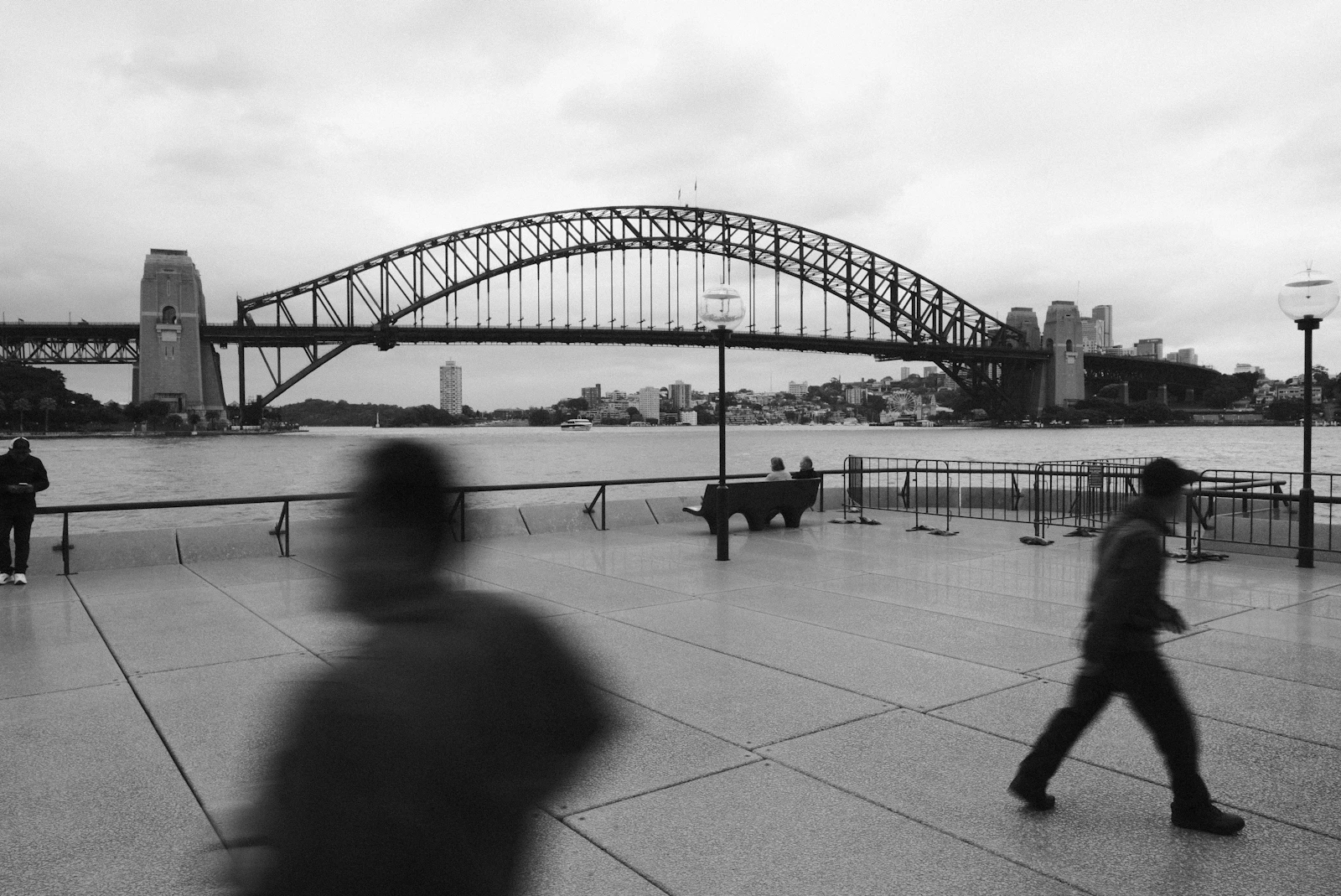 Black and white photo of people walking near the Sydney Harbour Bridge