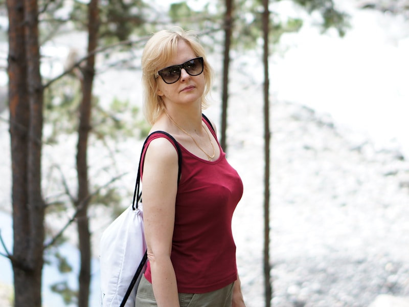 Stilvolle Frau in rotem Shirt und Sonnenbrille im Wald