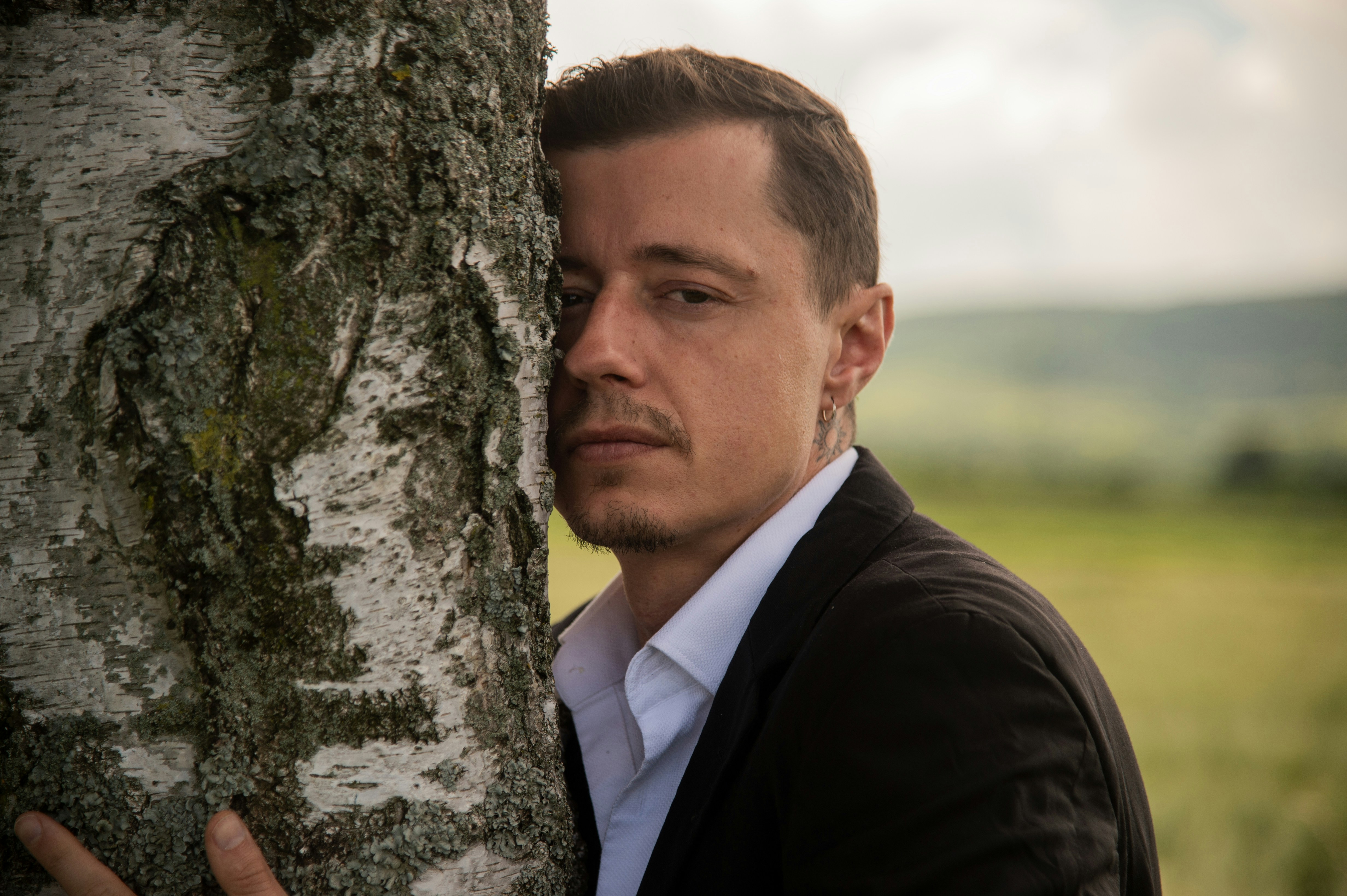 A man leaning against a tree in a field