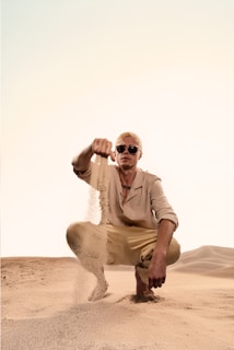 A man kneeling down in the middle of a desert
