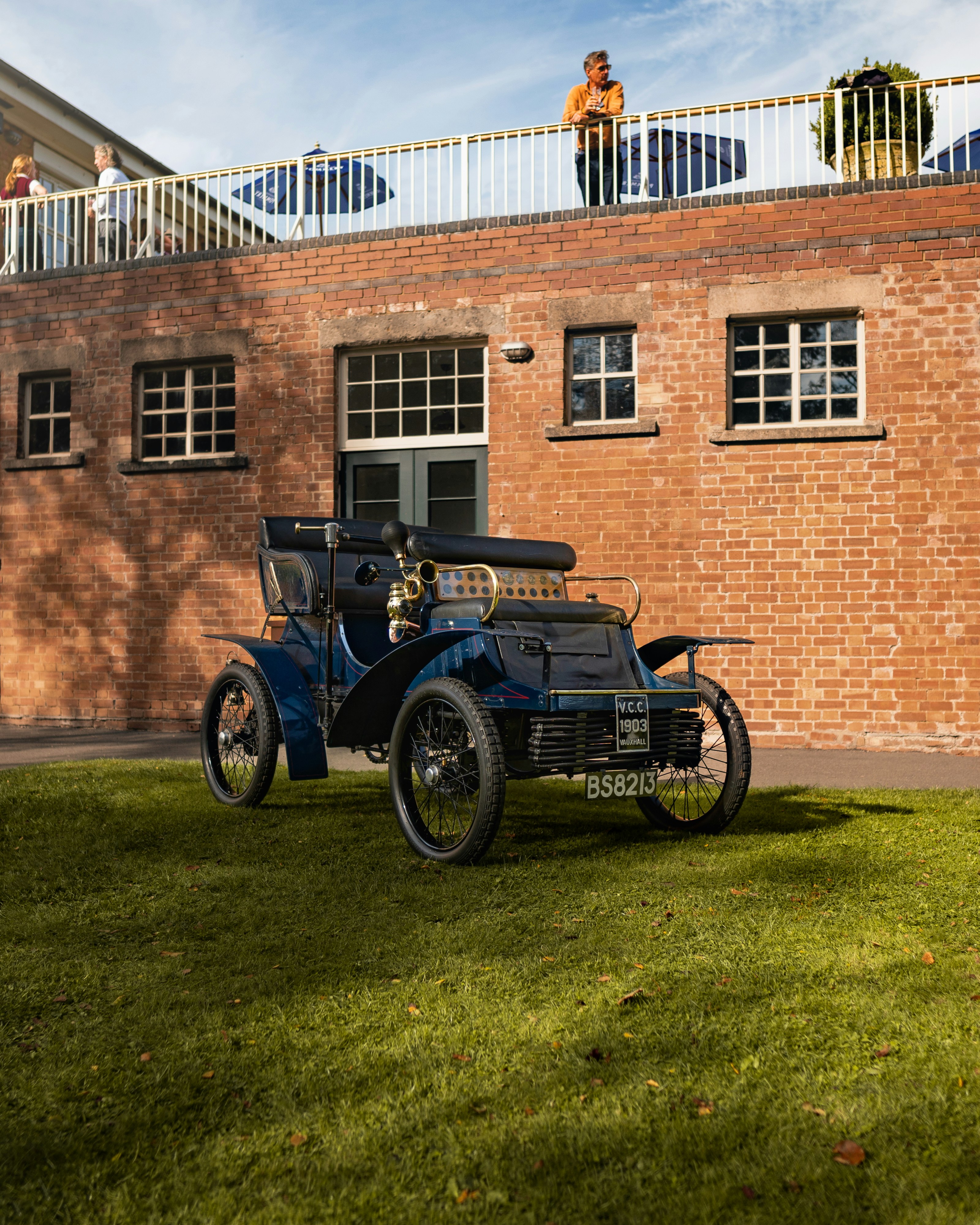 An old car parked in front of a brick building