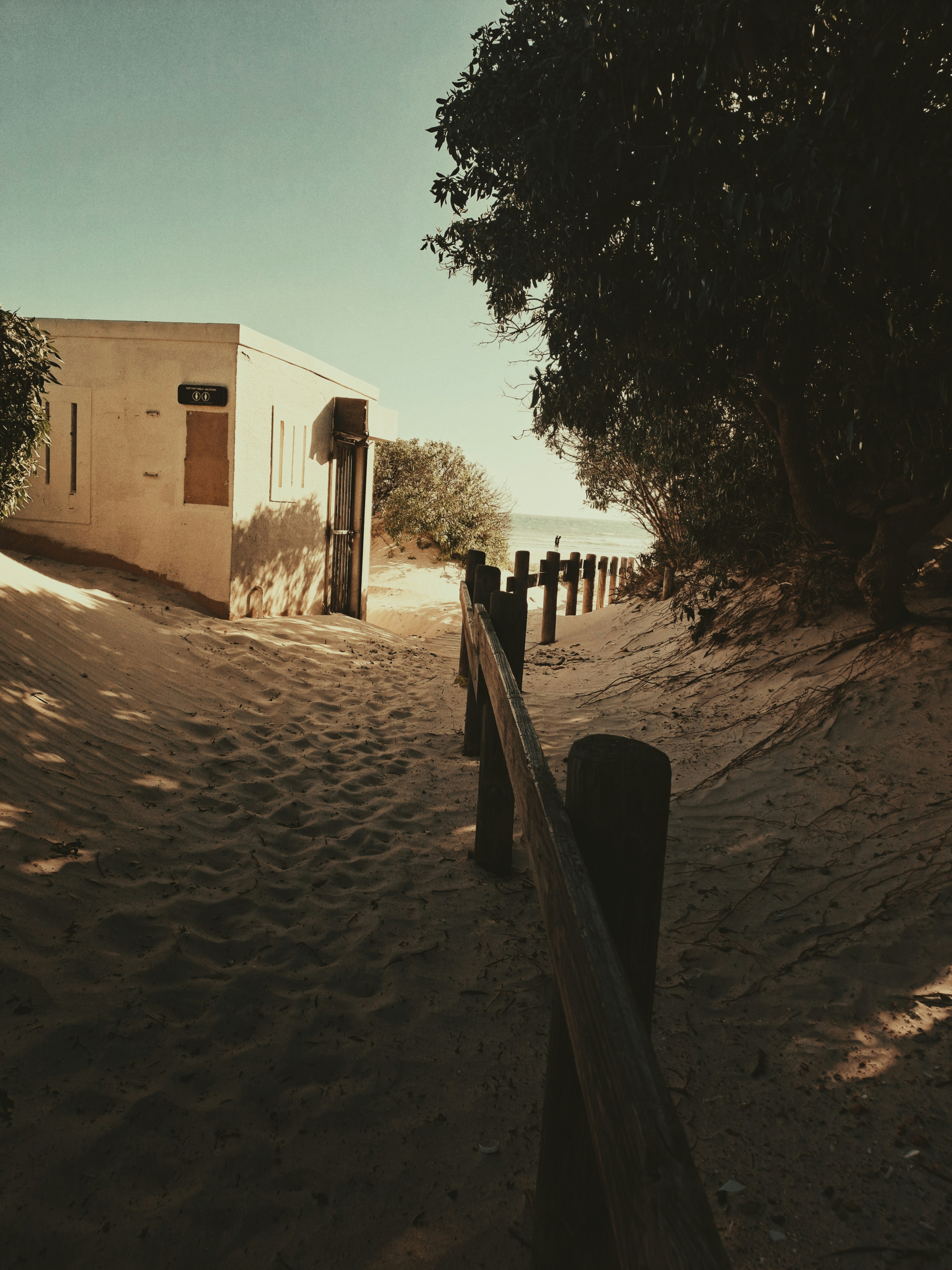 Uma estrada de terra com uma cerca e um prédio ao fundo