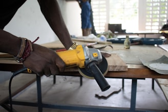 A man is using a drill to drill a piece of wood