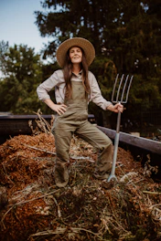 A woman in overalls and a straw hat holding a pitchfork