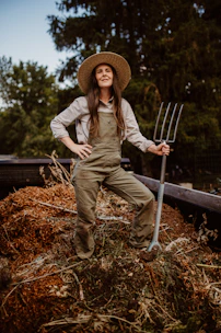 A woman in overalls and a straw hat holding a pitchfork