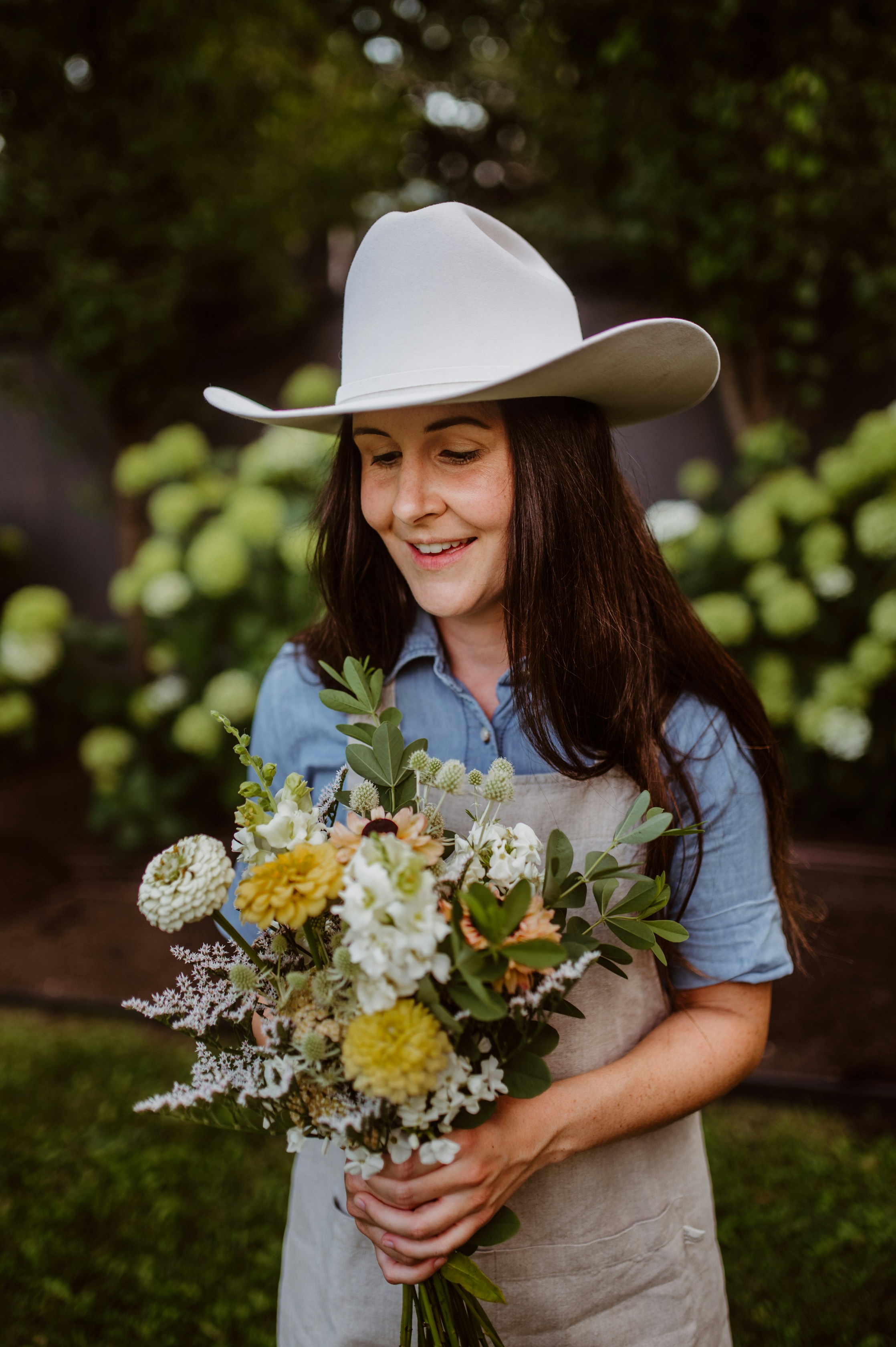 Una mujer con un sombrero de vaquero sosteniendo un ramo de flores