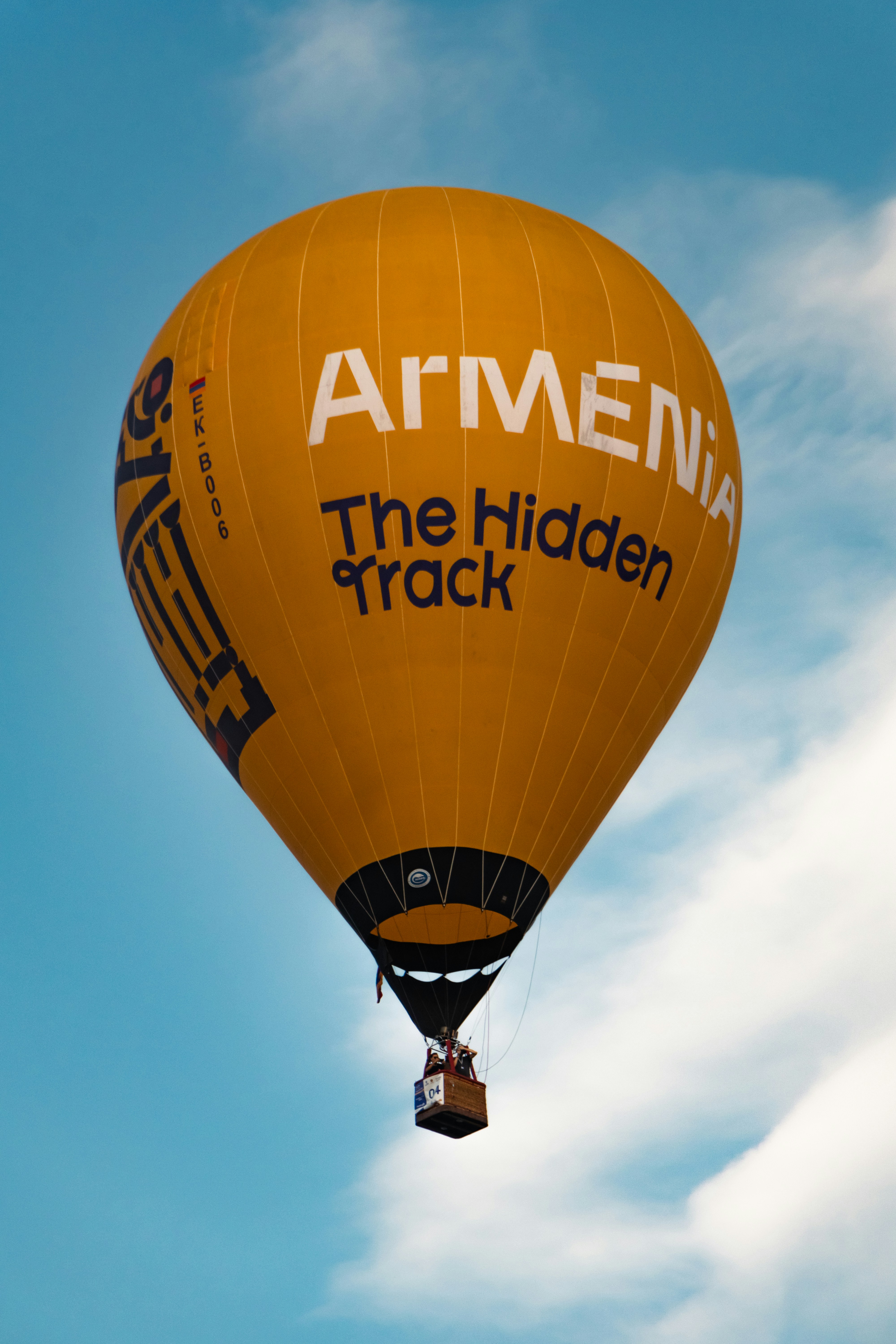 A yellow hot air balloon flying through a blue sky