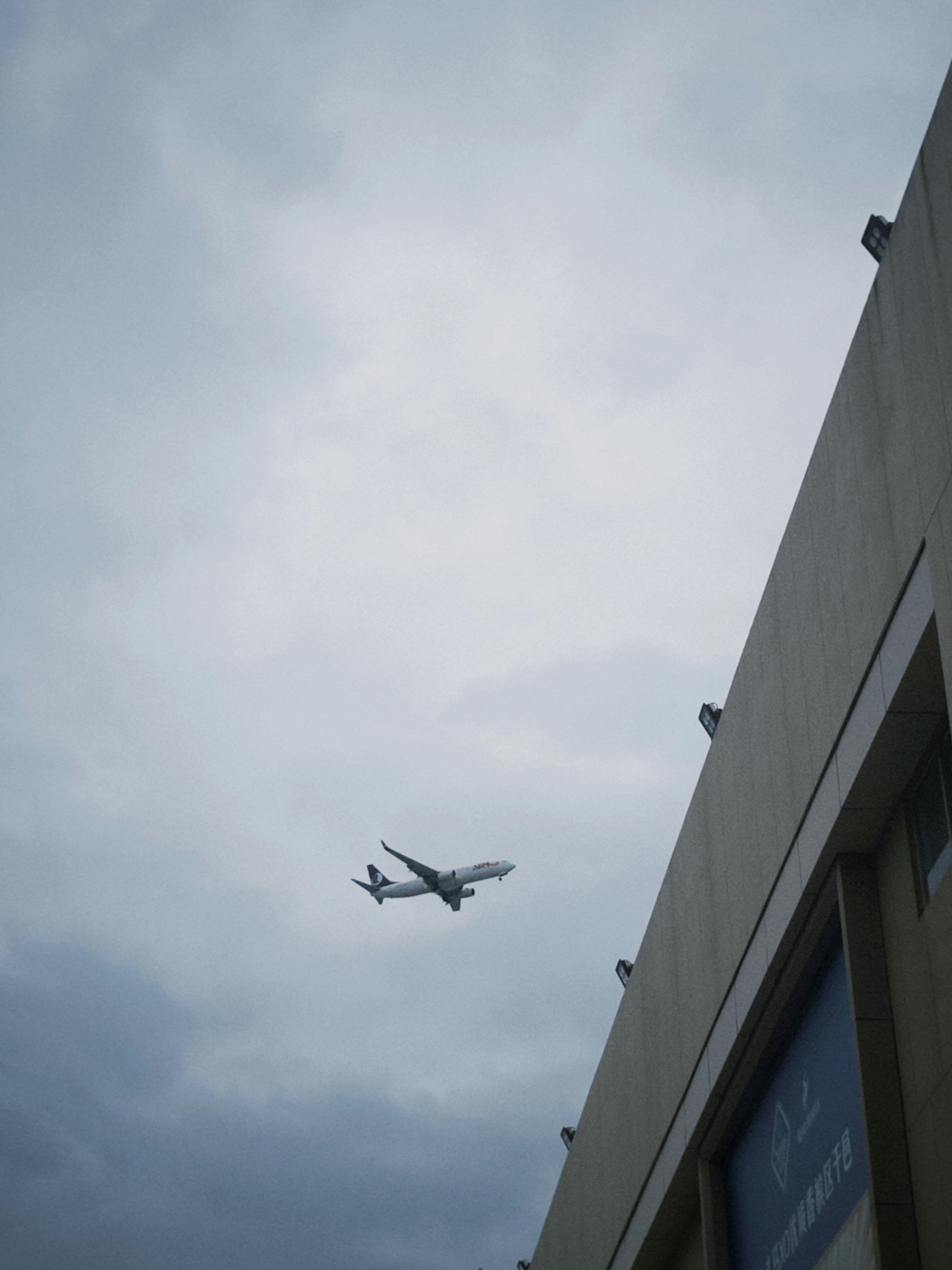 An airplane flying over a building on a cloudy day